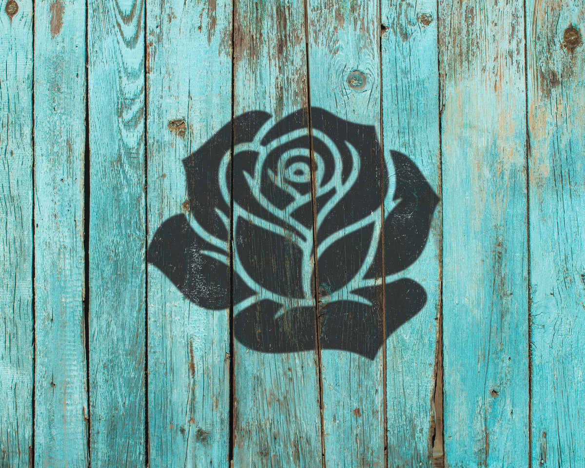 a black silhouette of a rose painted on a weathered, turquoise wooden surface.