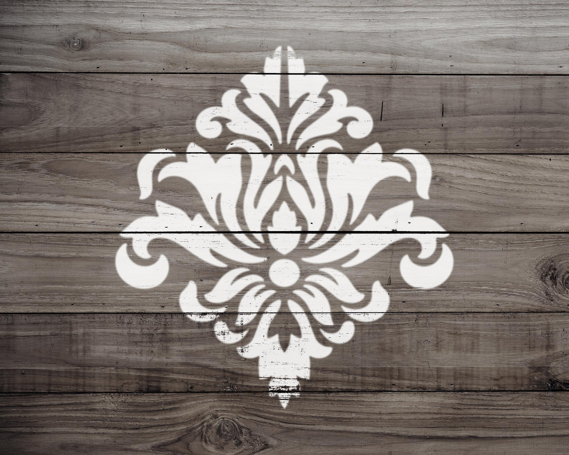 a white, ornate design resembling a floral pattern or a decorative element, painted on a wooden surface.