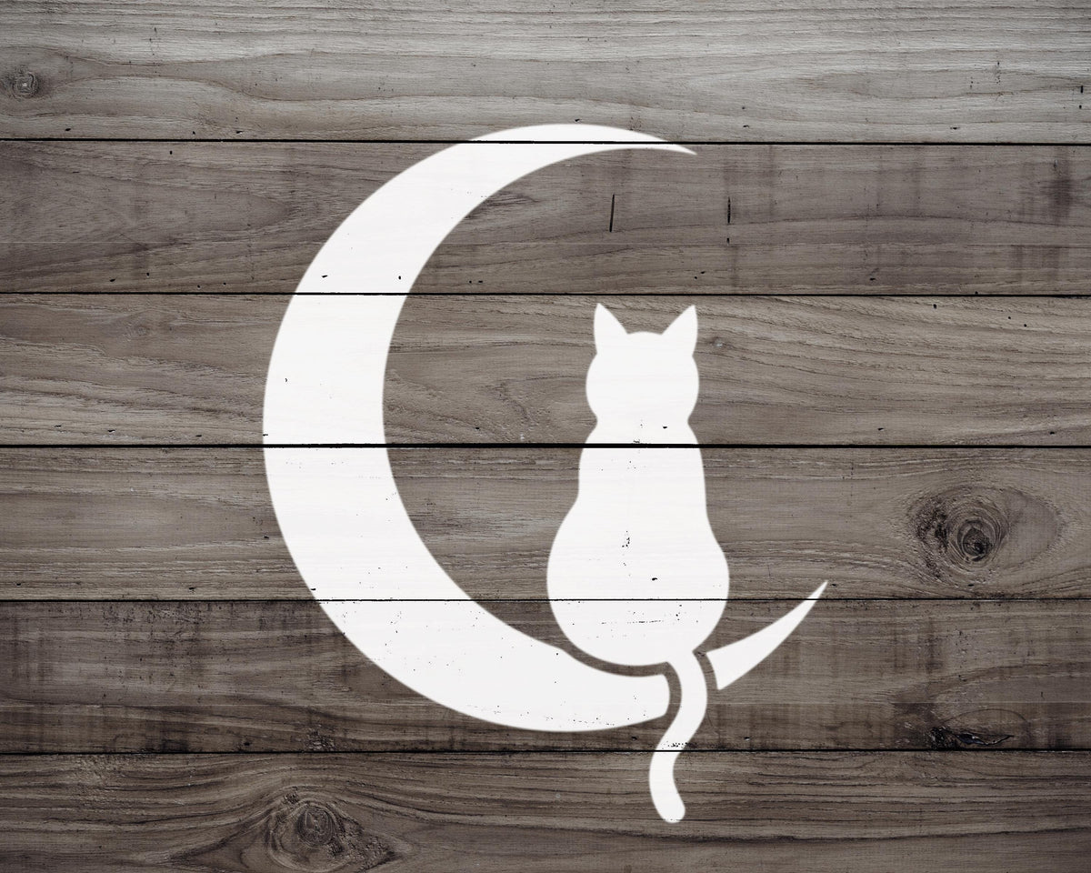 A white silhouette of a cat sitting on a crescent moon against a wooden background.