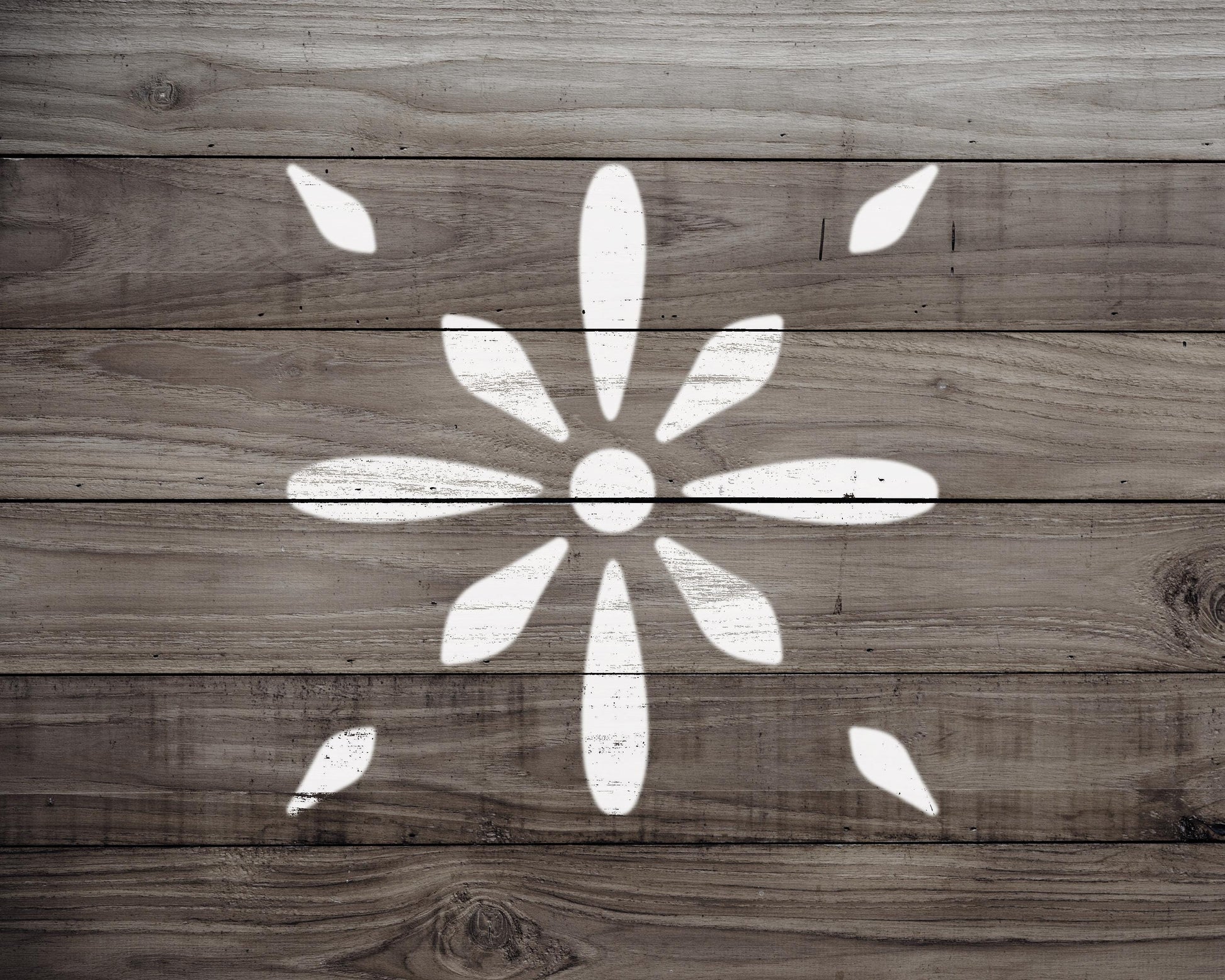 a wooden surface with a white flower-like design painted on it.