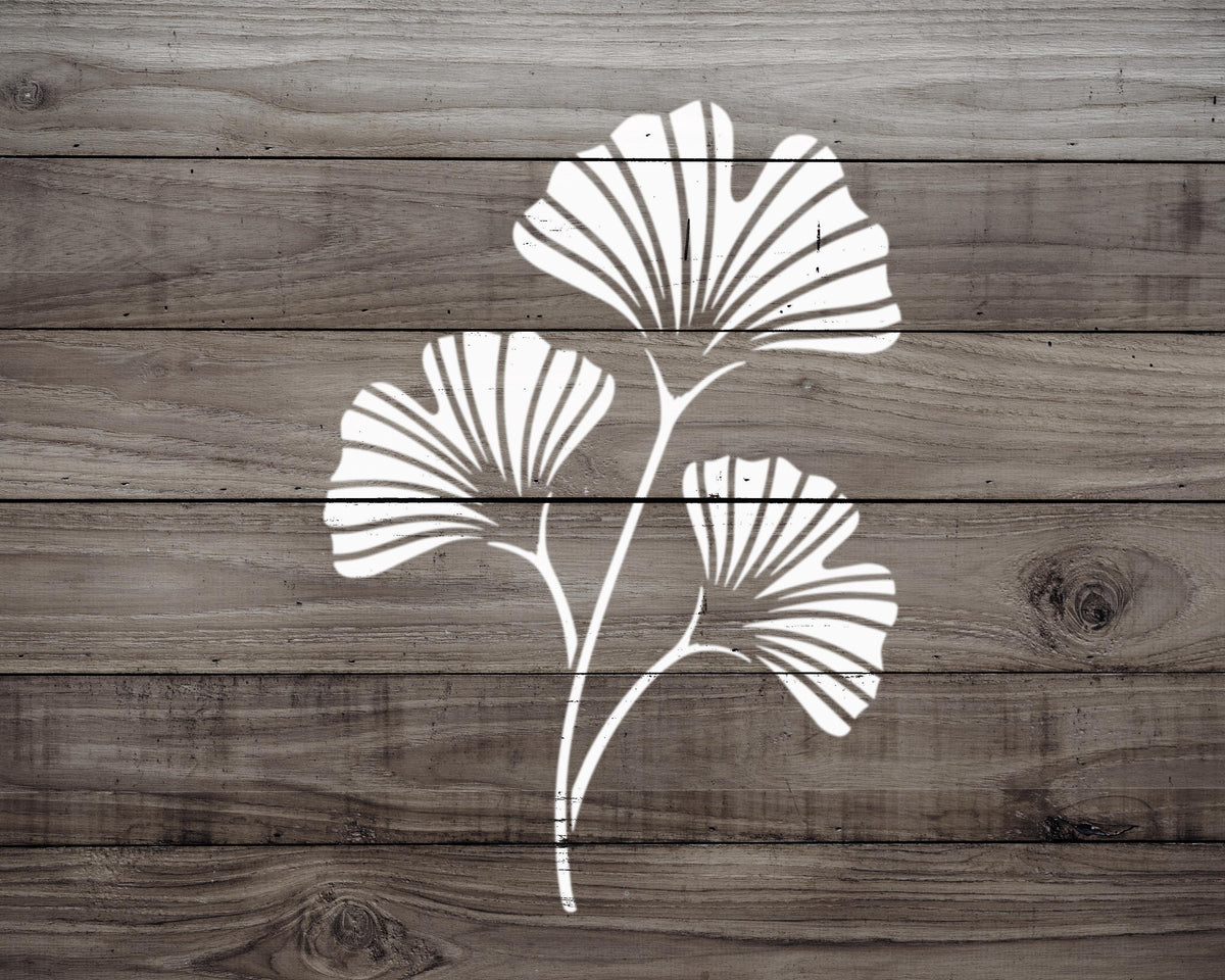 A white silhouette of a ginkgo tree with three leaves is displayed on a wooden surface.