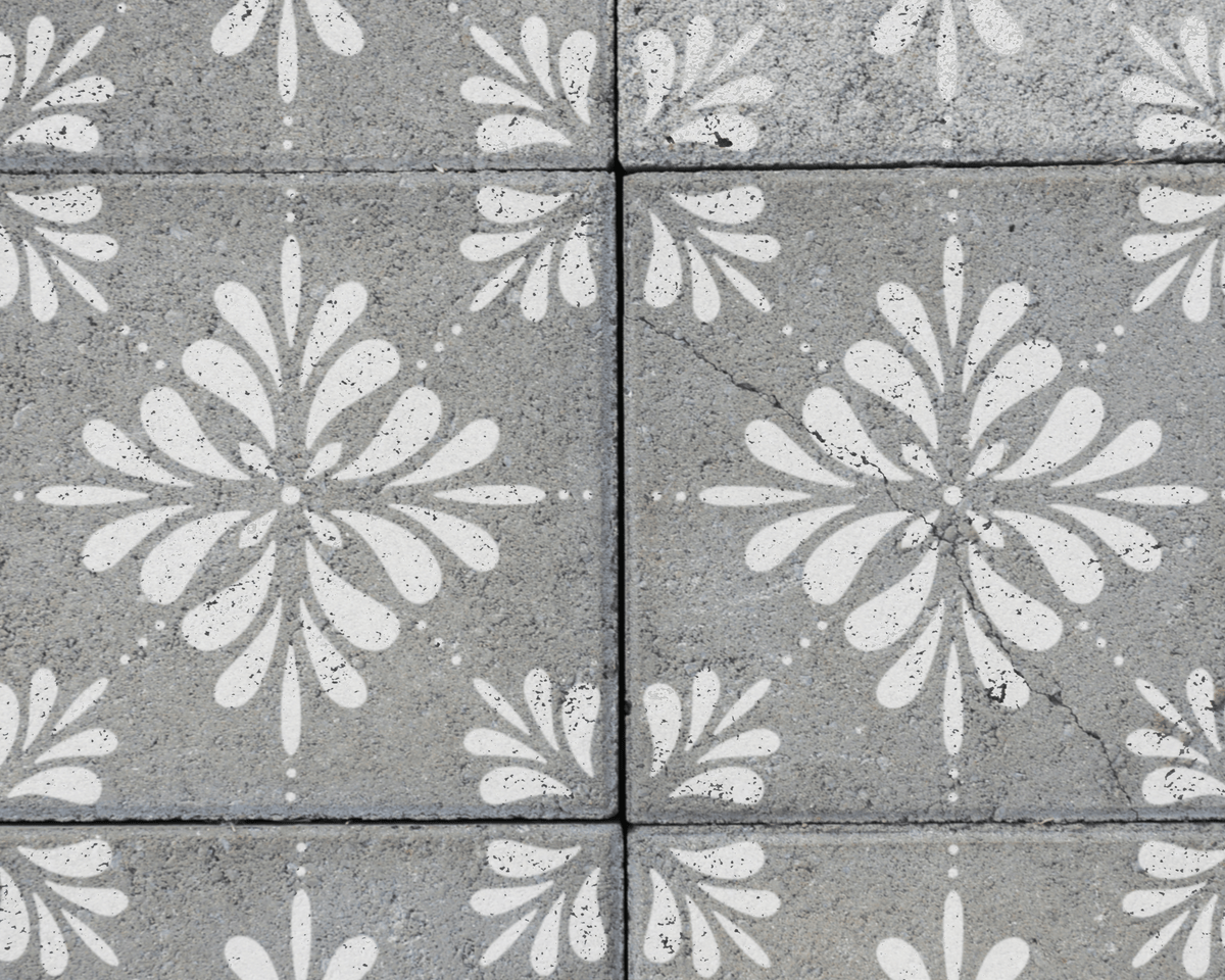a close-up view of a patterned concrete surface, featuring a repeating design of white floral motifs.