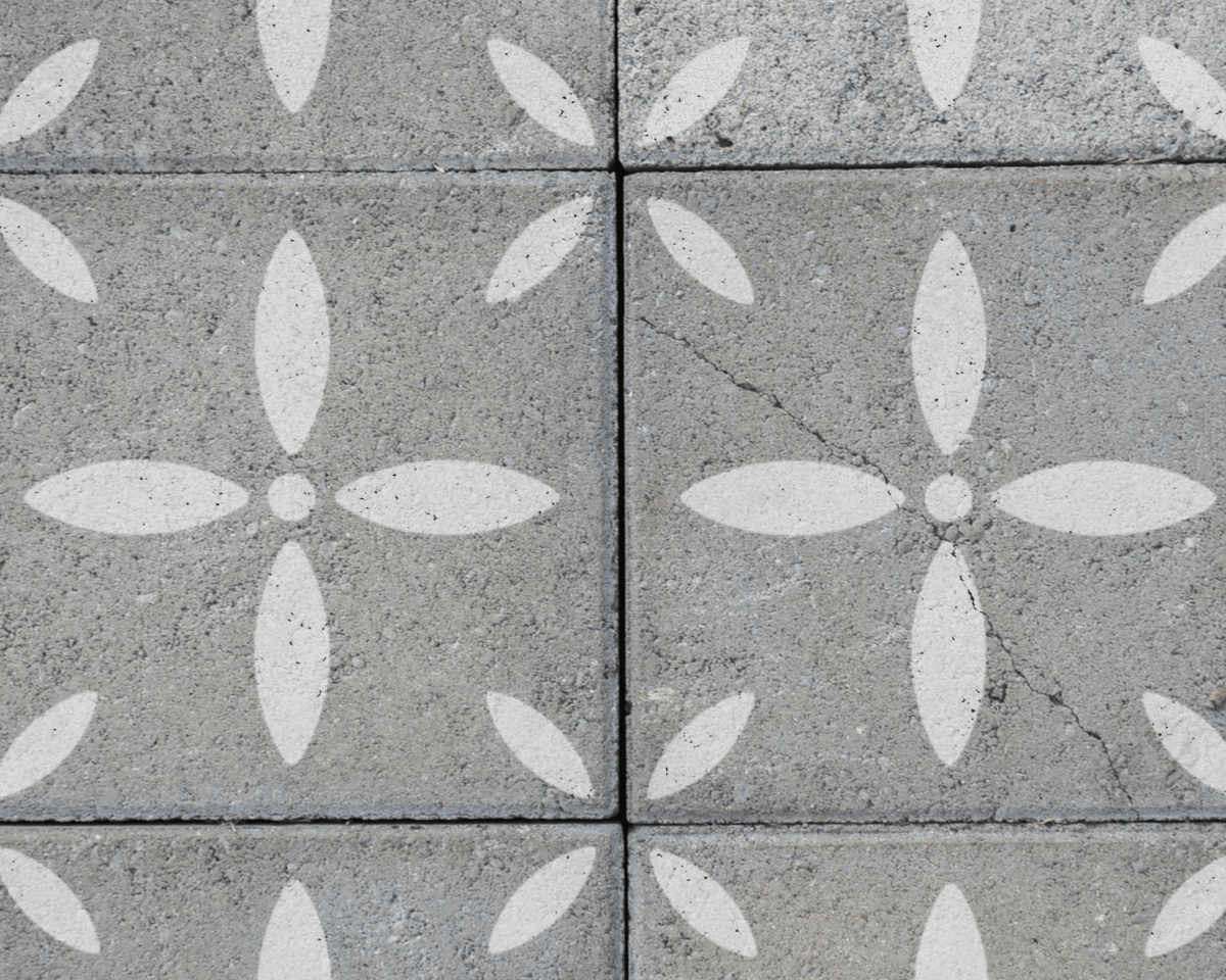 a close-up view of a patterned concrete surface, featuring a repeating design of white flower-like shapes.