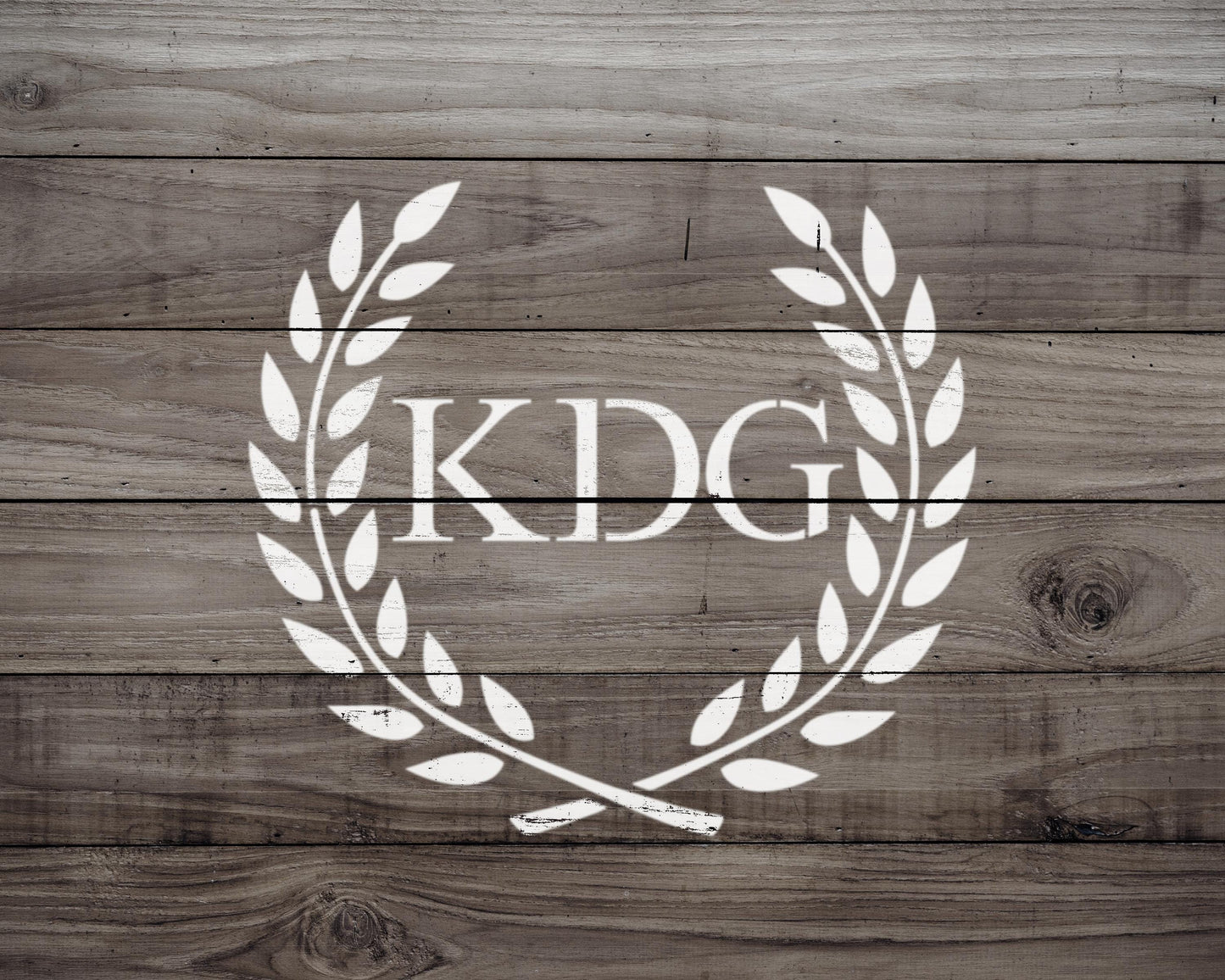 a logo consisting of a laurel wreath with the letters 'KDG' inside it, all set against a wooden background.