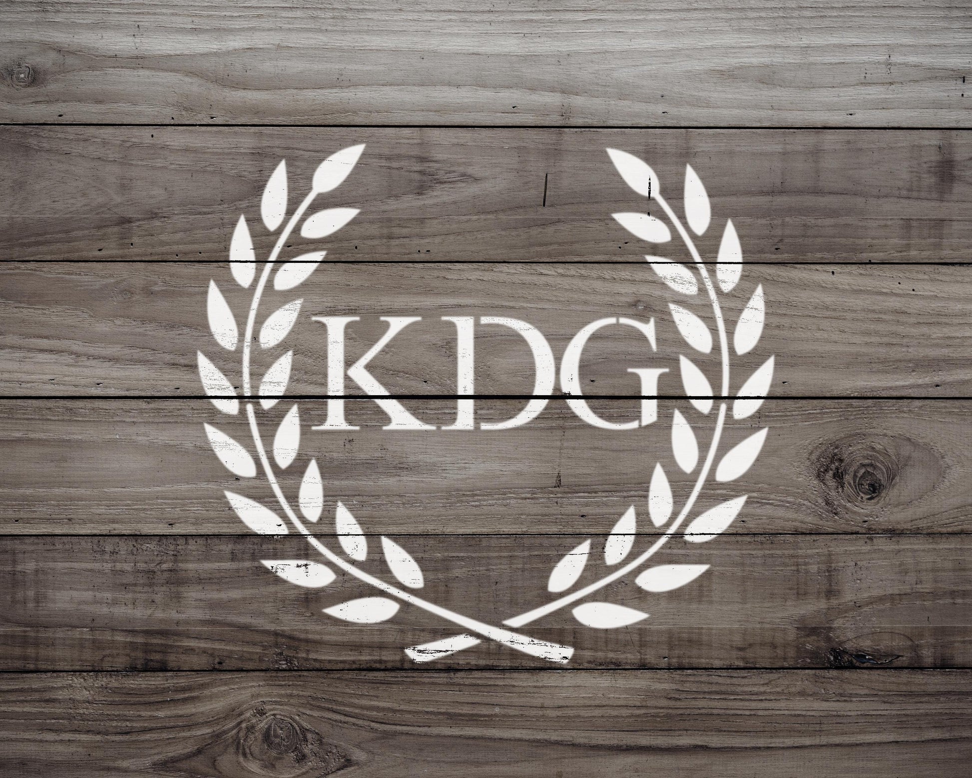a logo consisting of a laurel wreath with the letters 'KDG' inside it, all set against a wooden background.