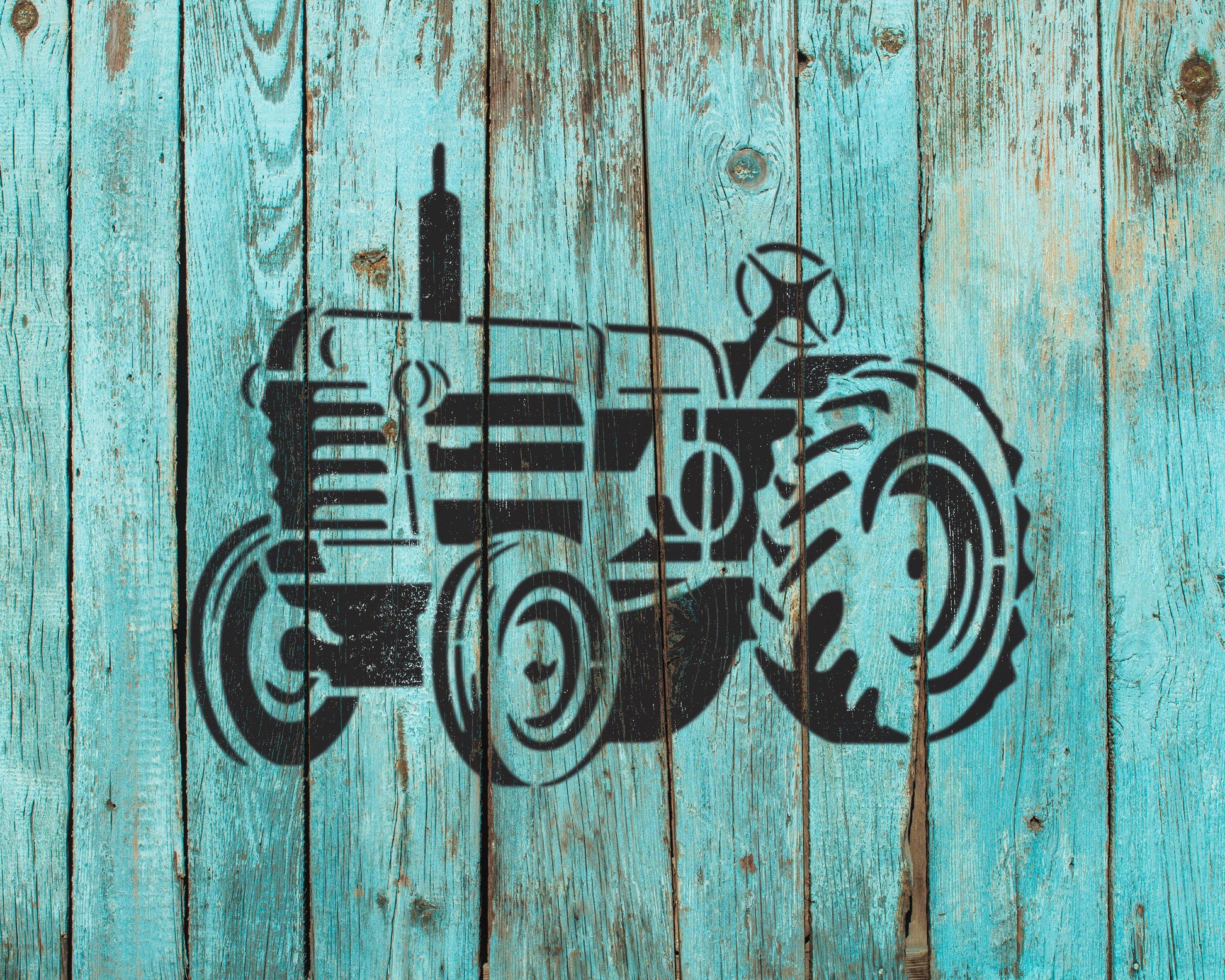 A black silhouette of a tractor is painted on a weathered blue wooden surface.