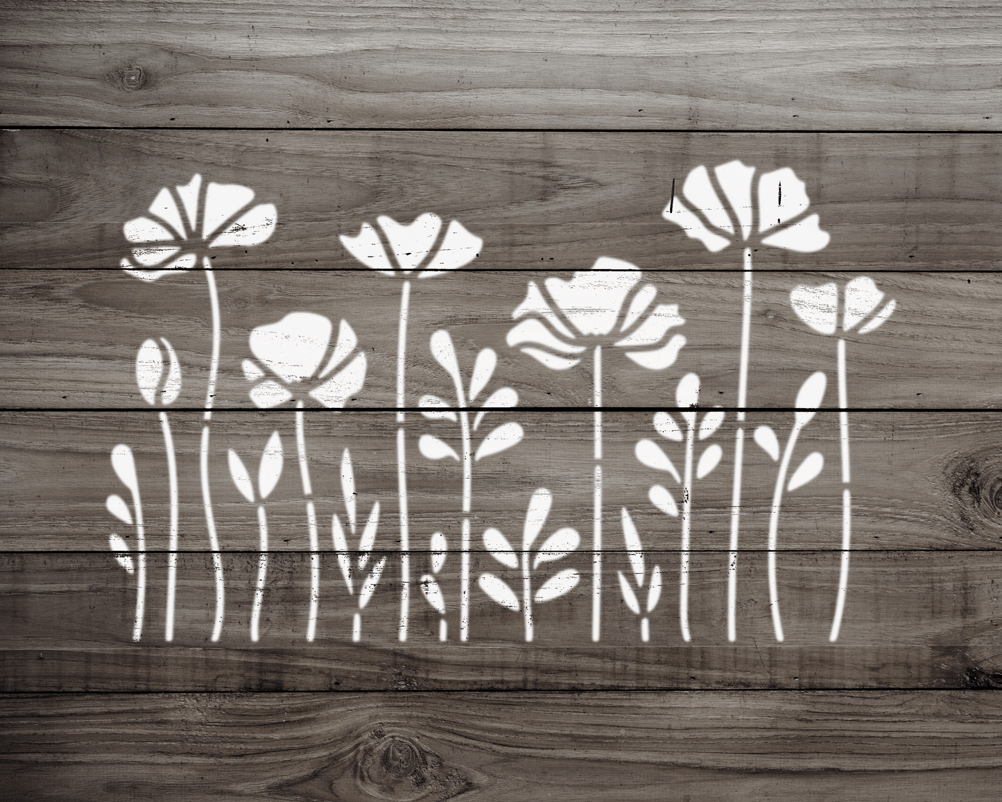 A wooden surface with a repeating pattern of white floral designs, including flowers and leaves, arranged in a row.