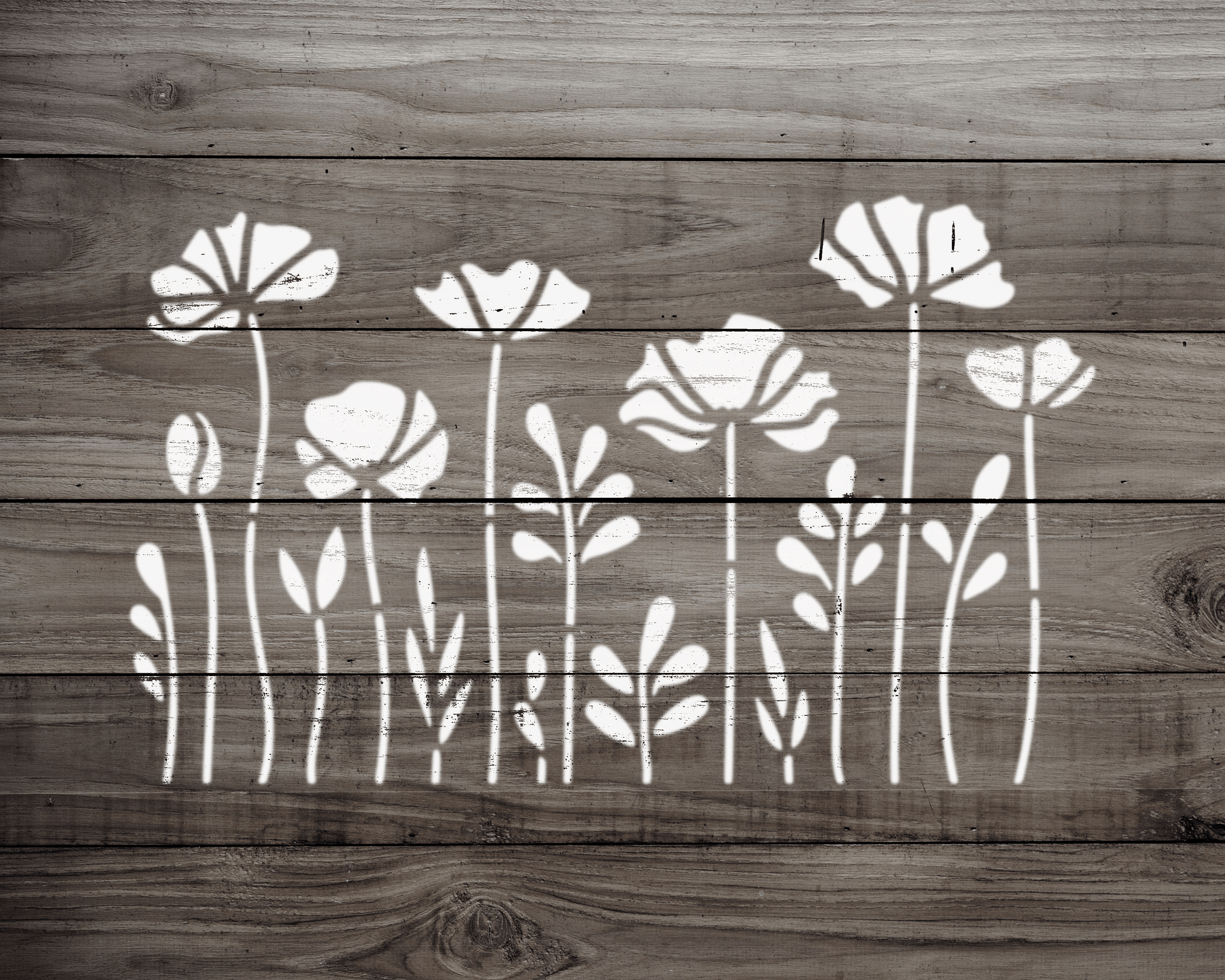 A wooden surface with a repeating pattern of white floral designs, including flowers and leaves, arranged in a row.