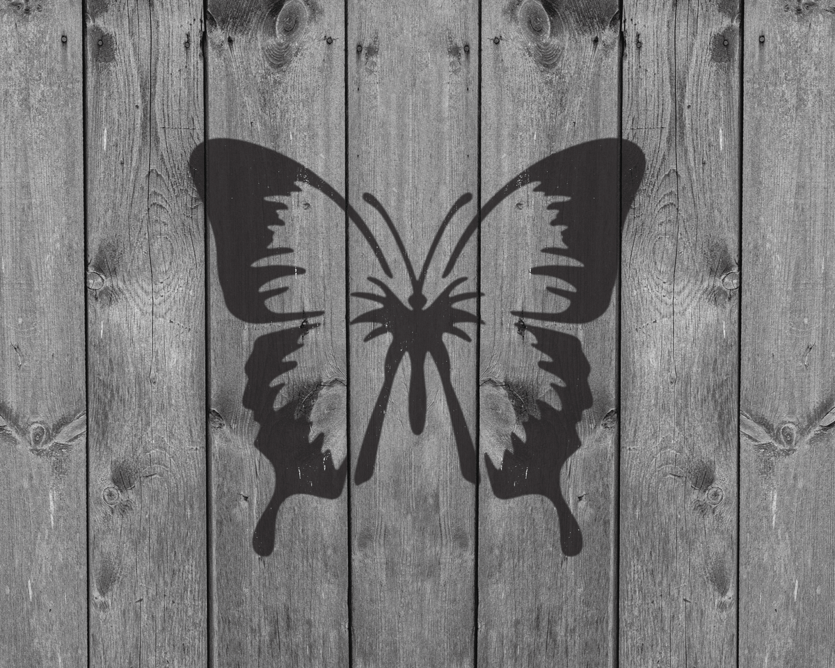 A black and white image of a butterfly printed on a wooden background.