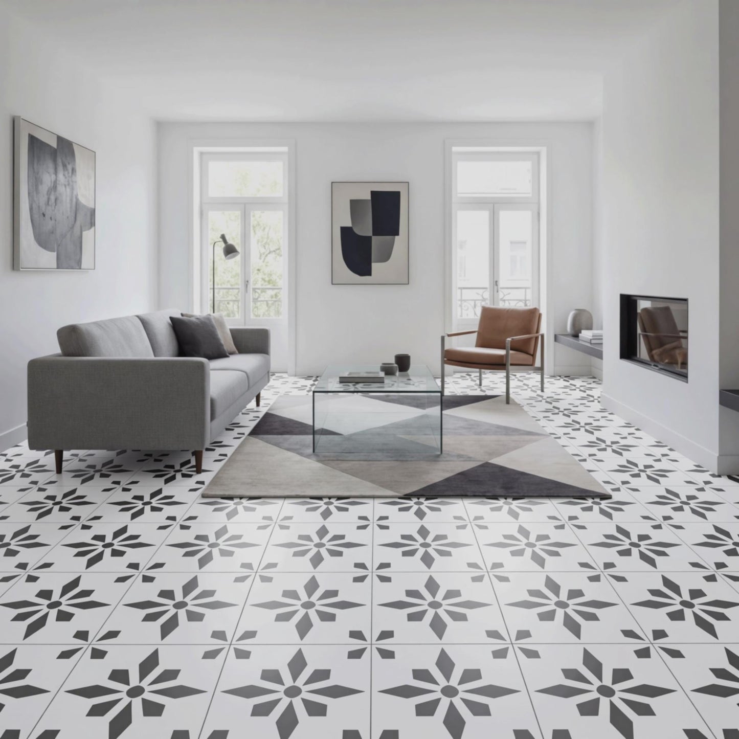 a modern living room with a gray sofa, a glass coffee table, and a brown leather armchair. The room has a white and black geometric tile floor, and there are two windows with white curtains. The walls are painted white, and there are two abstract paintings hanging on the wall.