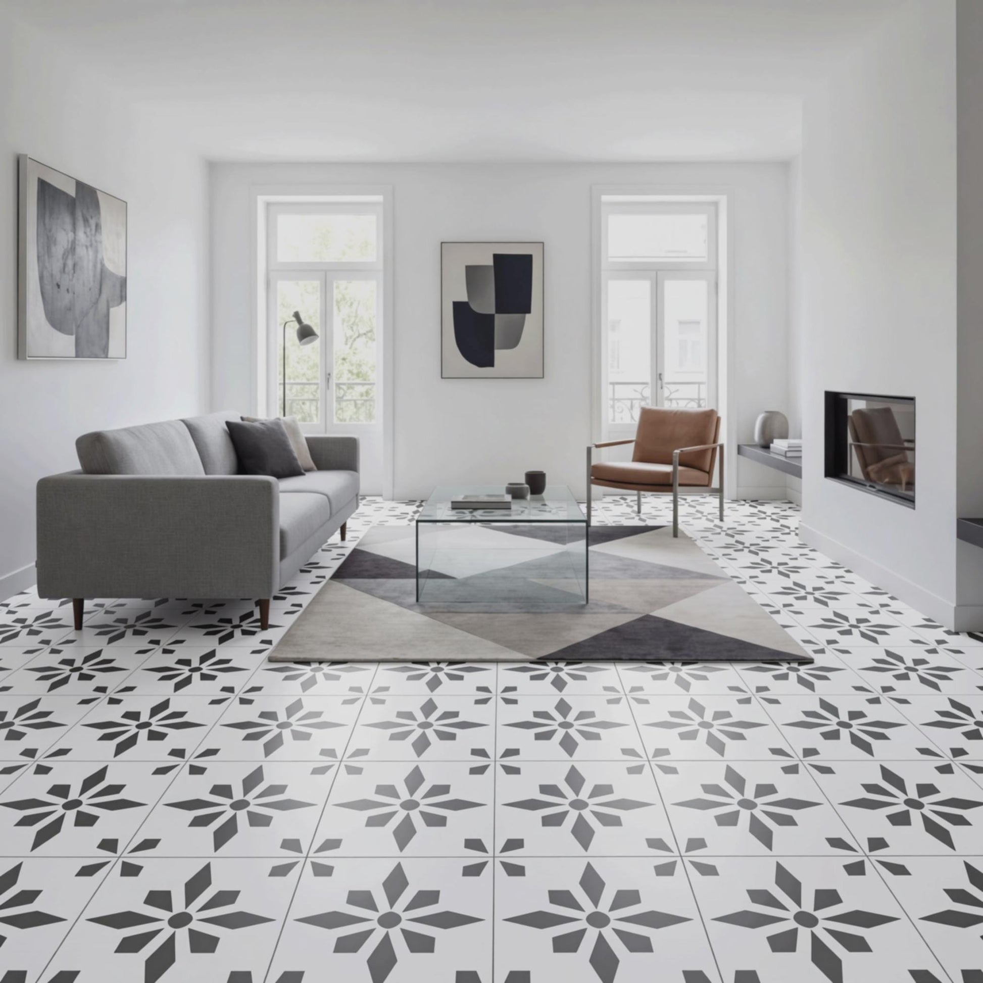 a modern living room with a gray sofa, a glass coffee table, and a brown leather armchair. The room has a white and black geometric tile floor, and there are two windows with white curtains. The walls are painted white, and there are two abstract paintings hanging on the wall.