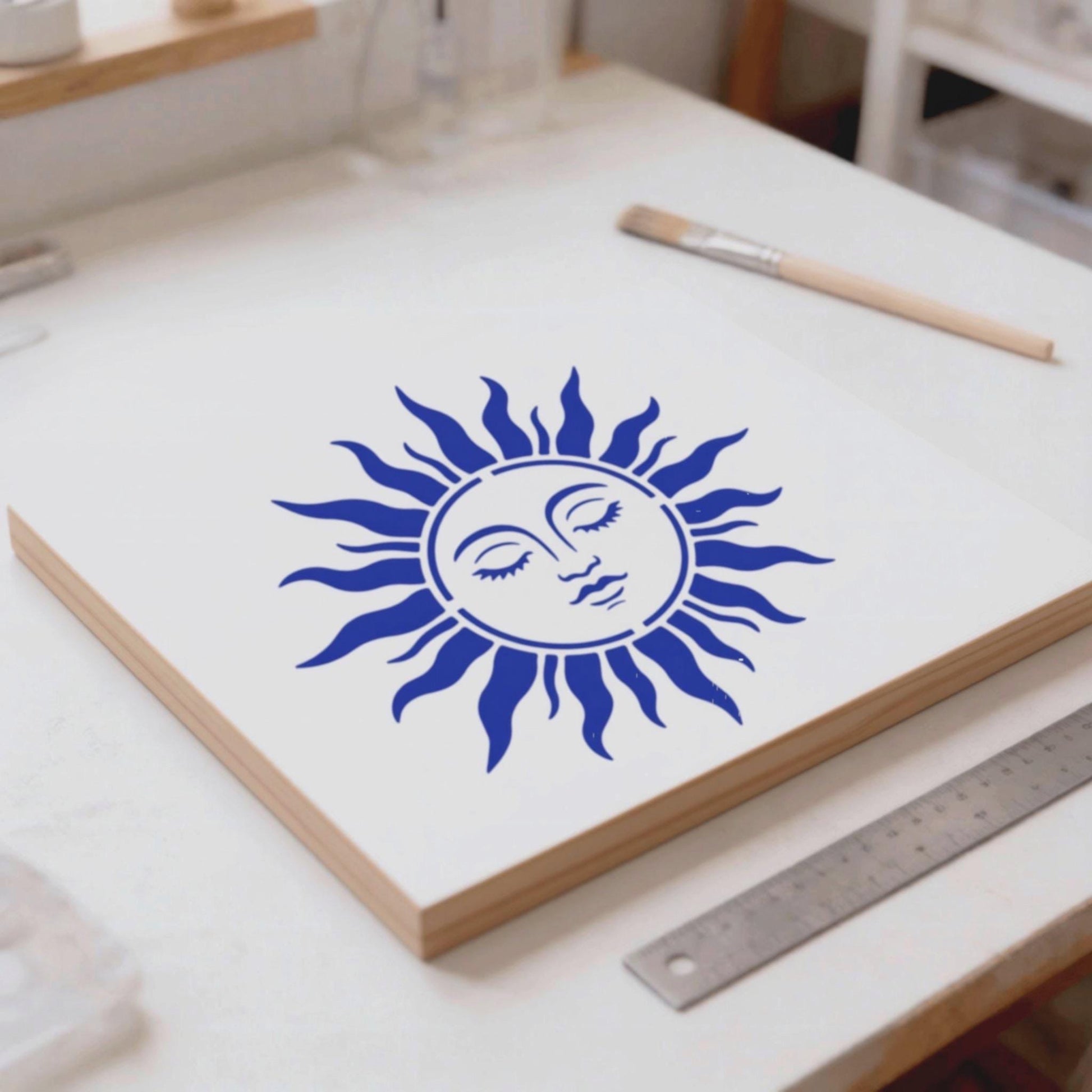 a white surface with a blue sun-like design on it, along with some art supplies and a ruler.
