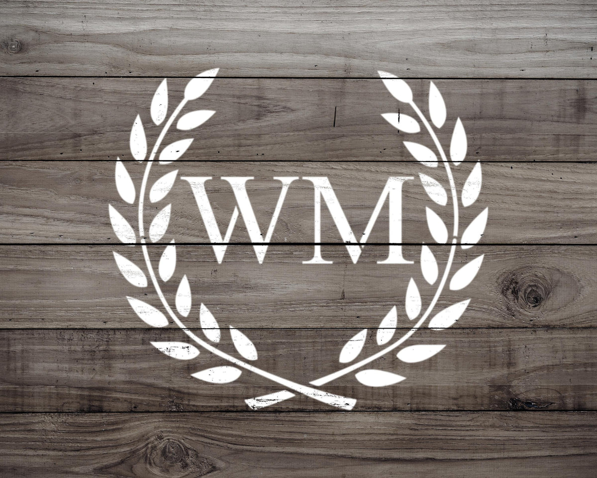 a logo consisting of the letters 'WM' in a laurel wreath design, set against a wooden background.