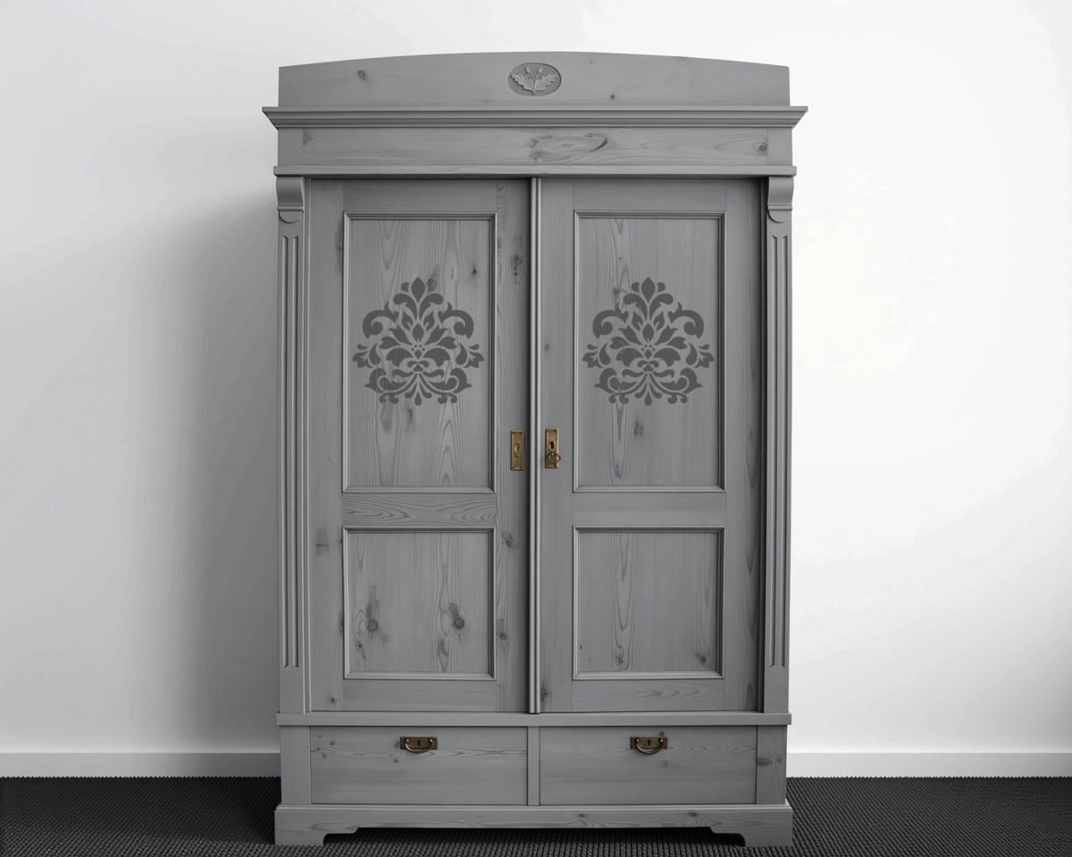 A gray wooden wardrobe with decorative floral patterns on the doors, standing against a white wall.
