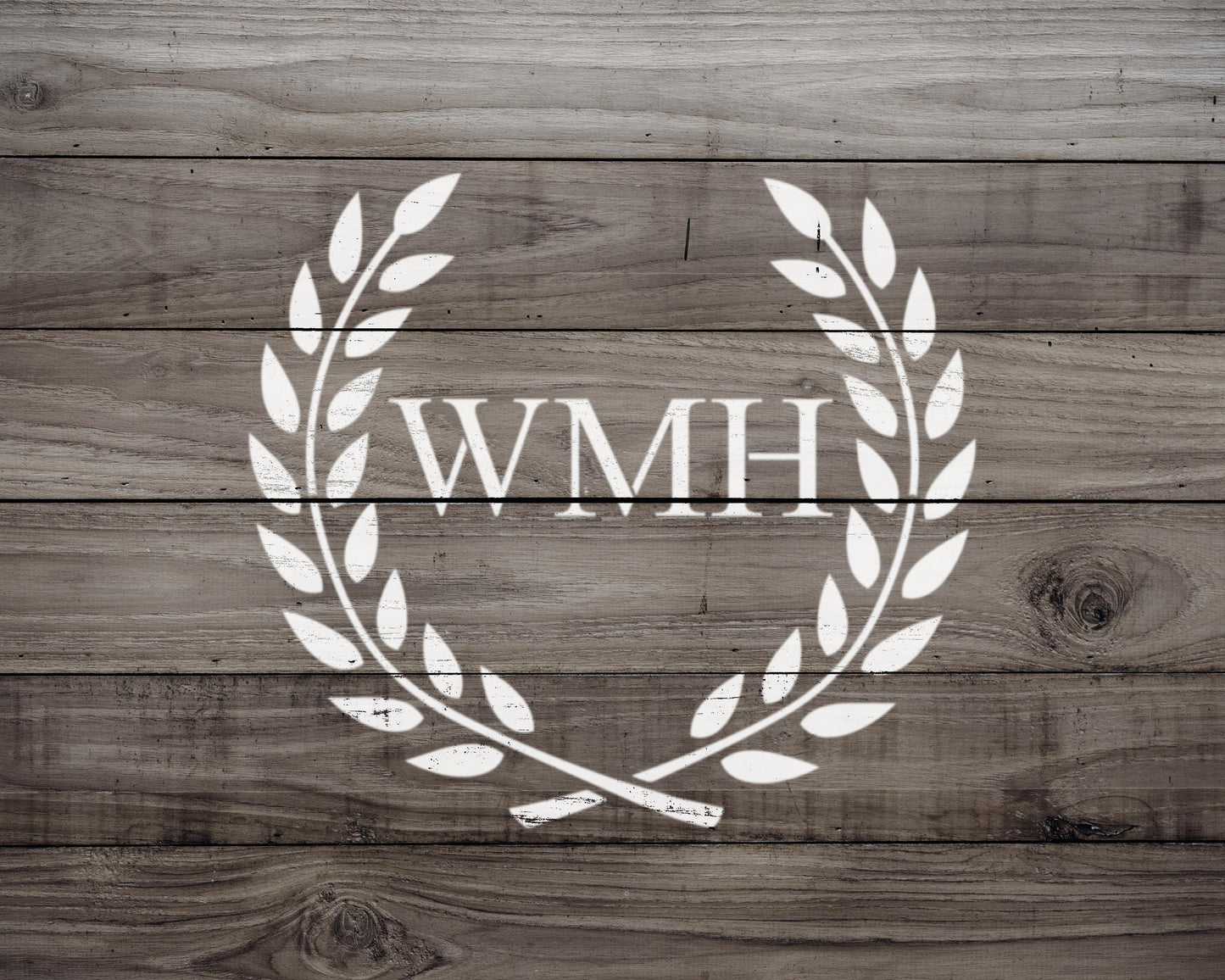 a wooden background with a white laurel wreath design containing the letters "WMH" in the center.