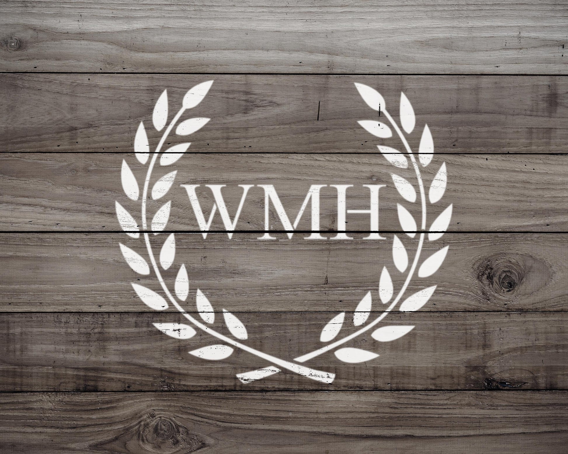 a wooden background with a white laurel wreath design containing the letters "WMH" in the center.