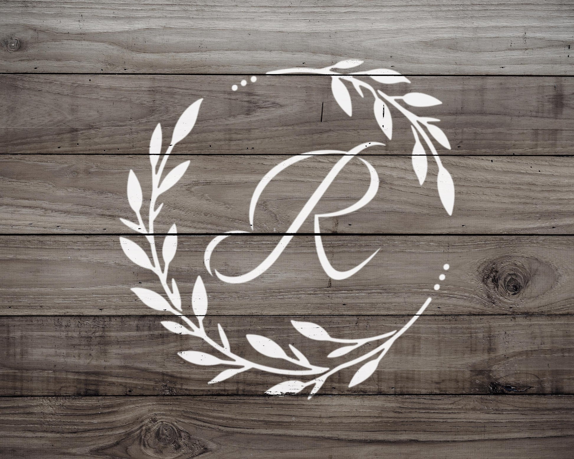 A monogrammed white letter "R" is displayed on a wooden background.