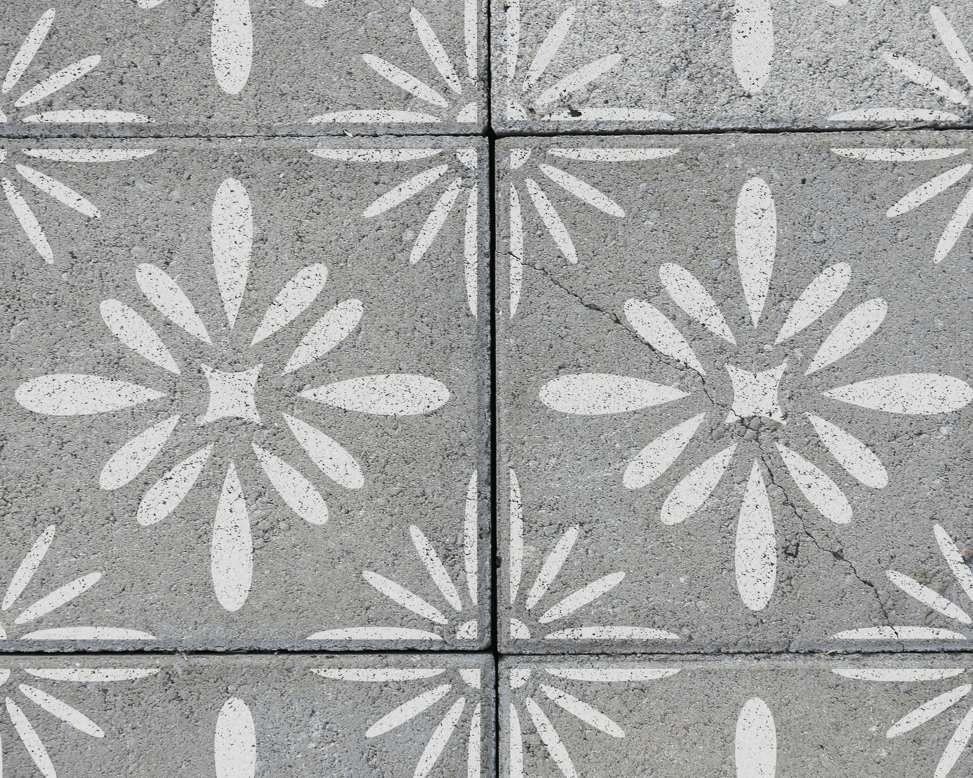 a close-up view of a concrete surface with a repeating pattern of white flower-like designs. The pattern is composed of various shapes and sizes, creating a visually interesting and intricate design.