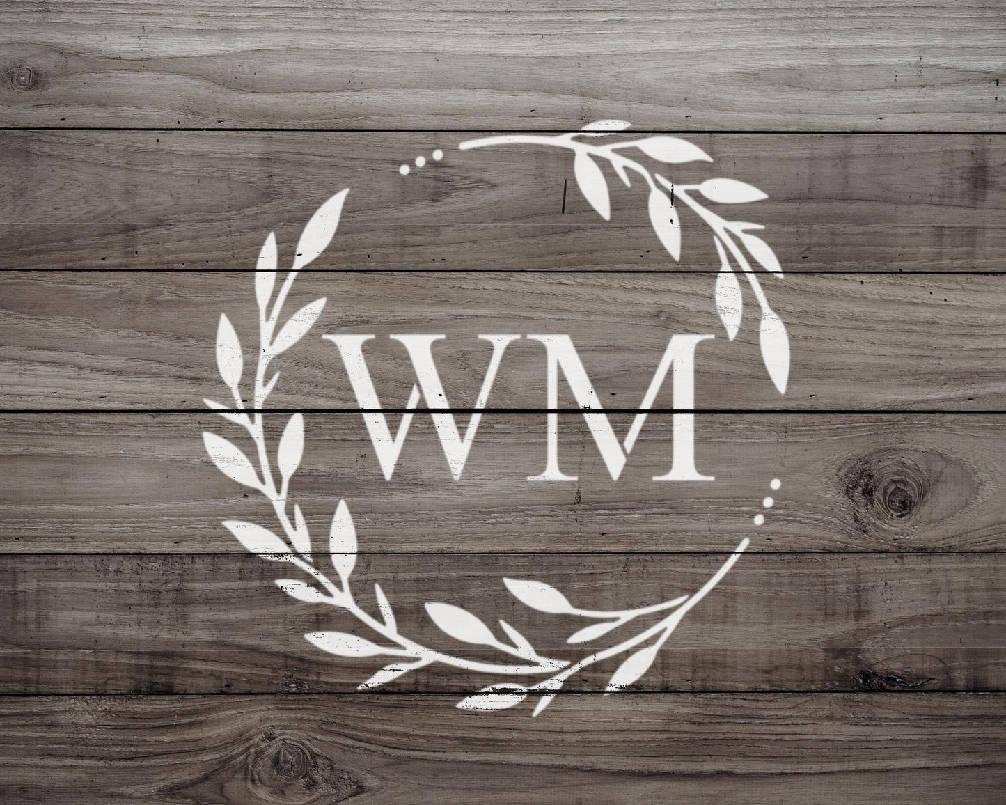 A monogrammed wreath made of white leaves and branches, with the letters "WM" prominently displayed in the center.