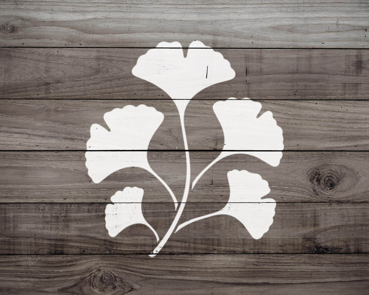 A white silhouette of a ginkgo tree is displayed on a wooden background.