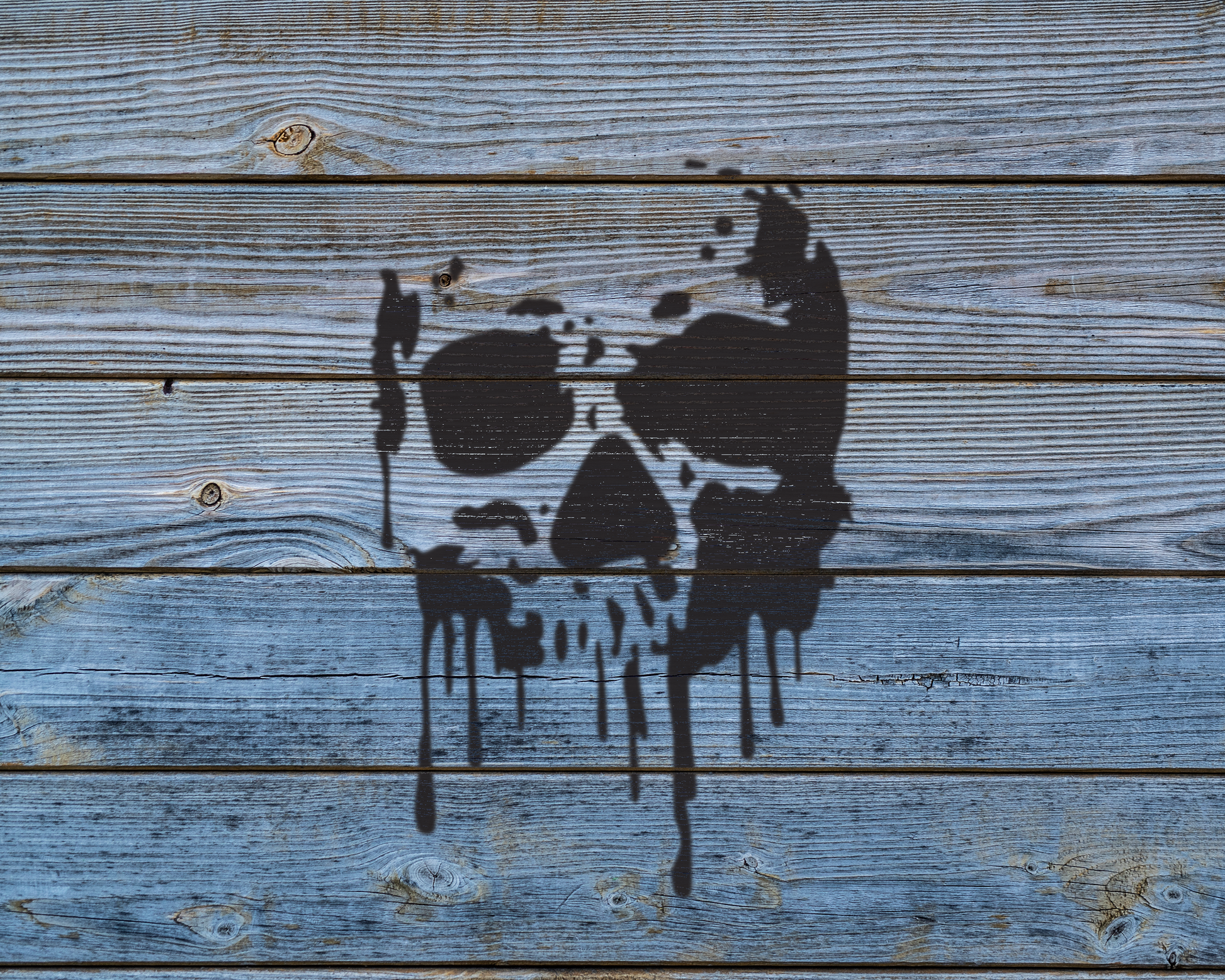 a wooden surface with a black, dripping, graffiti-like design resembling a skull or skull-like shape.