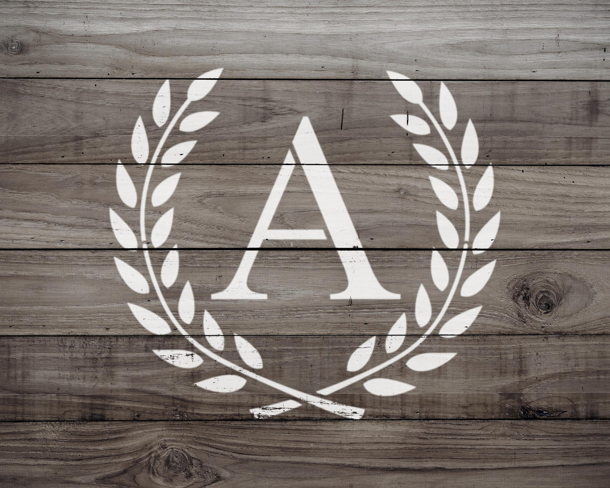 A monogrammed letter "A" in the center of a wreath made of leaves on a wooden background.