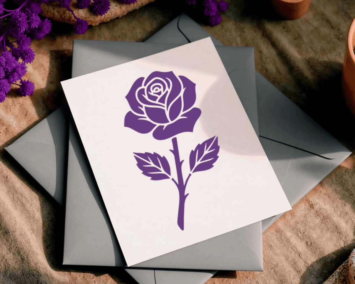 A white card with a purple rose design is placed on top of two gray envelopes, with purple flowers visible in the background.