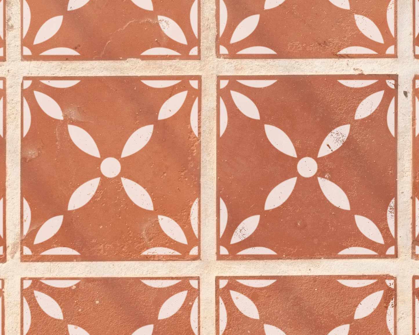 a close-up view of a patterned tile floor, featuring a repeating design of white floral motifs on a reddish-brown background.