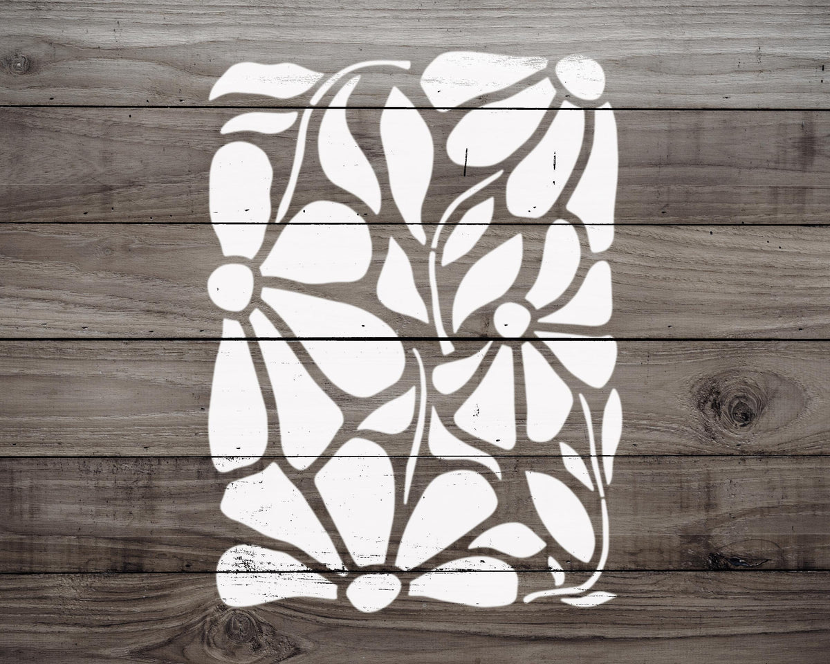 a white stencil of abstract floral or leaf-like shapes on a wooden background.