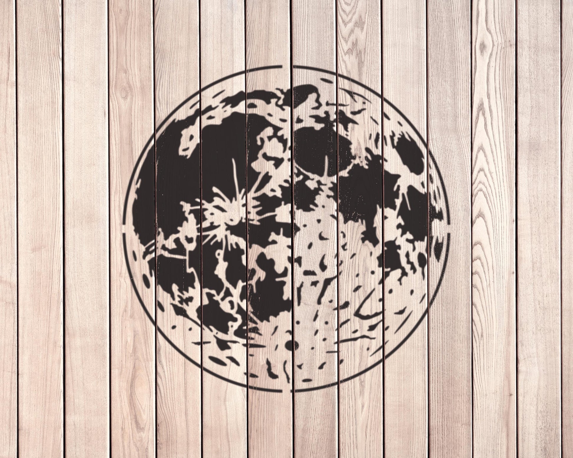 a large, circular black and white design resembling a moon or planet on a wooden background.