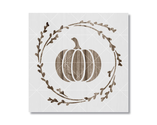 A white square with a wooden pumpkin silhouette and a wreath of leaves surrounding it.