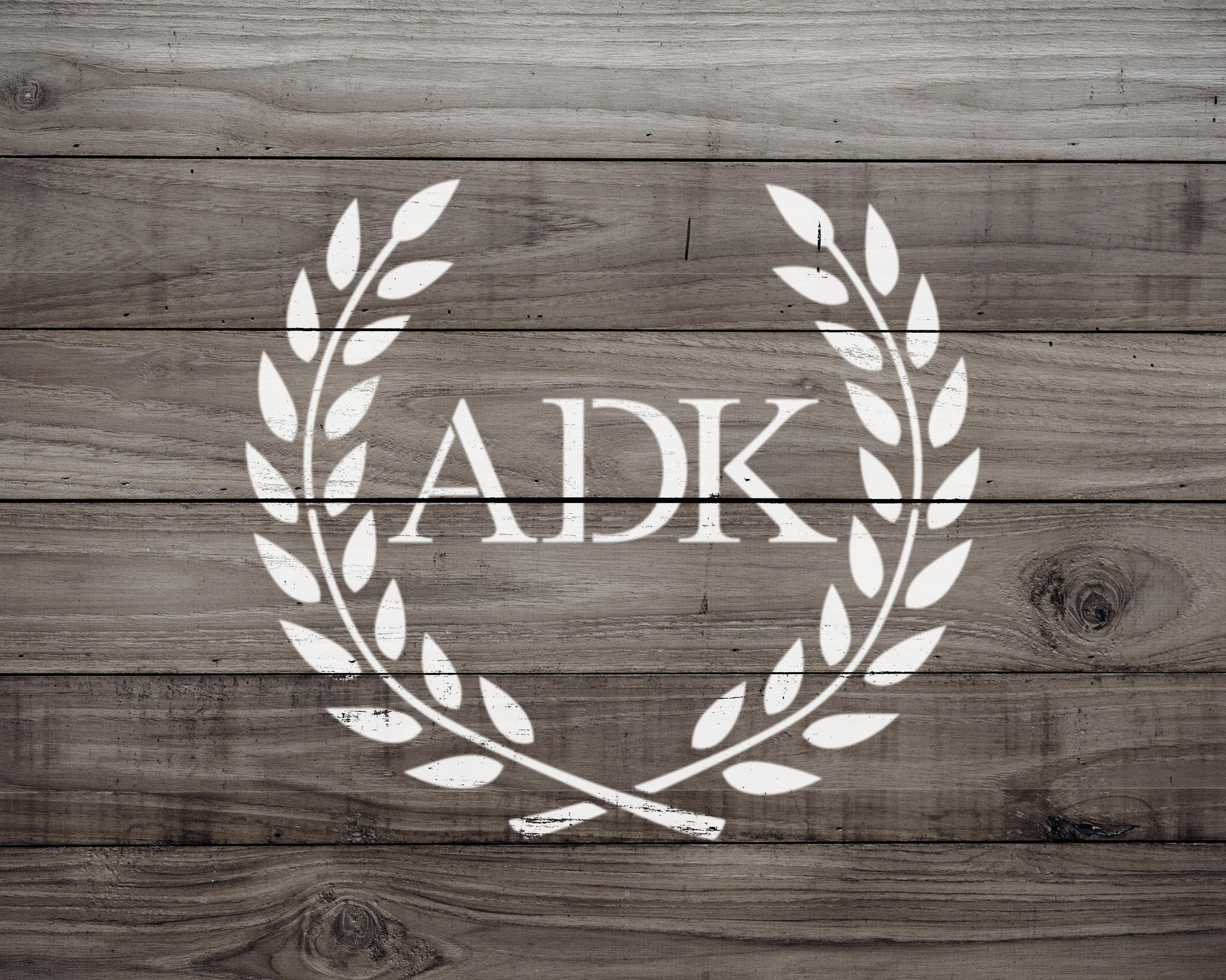 a logo with the letters 'ADK' in the center, surrounded by a laurel wreath design.