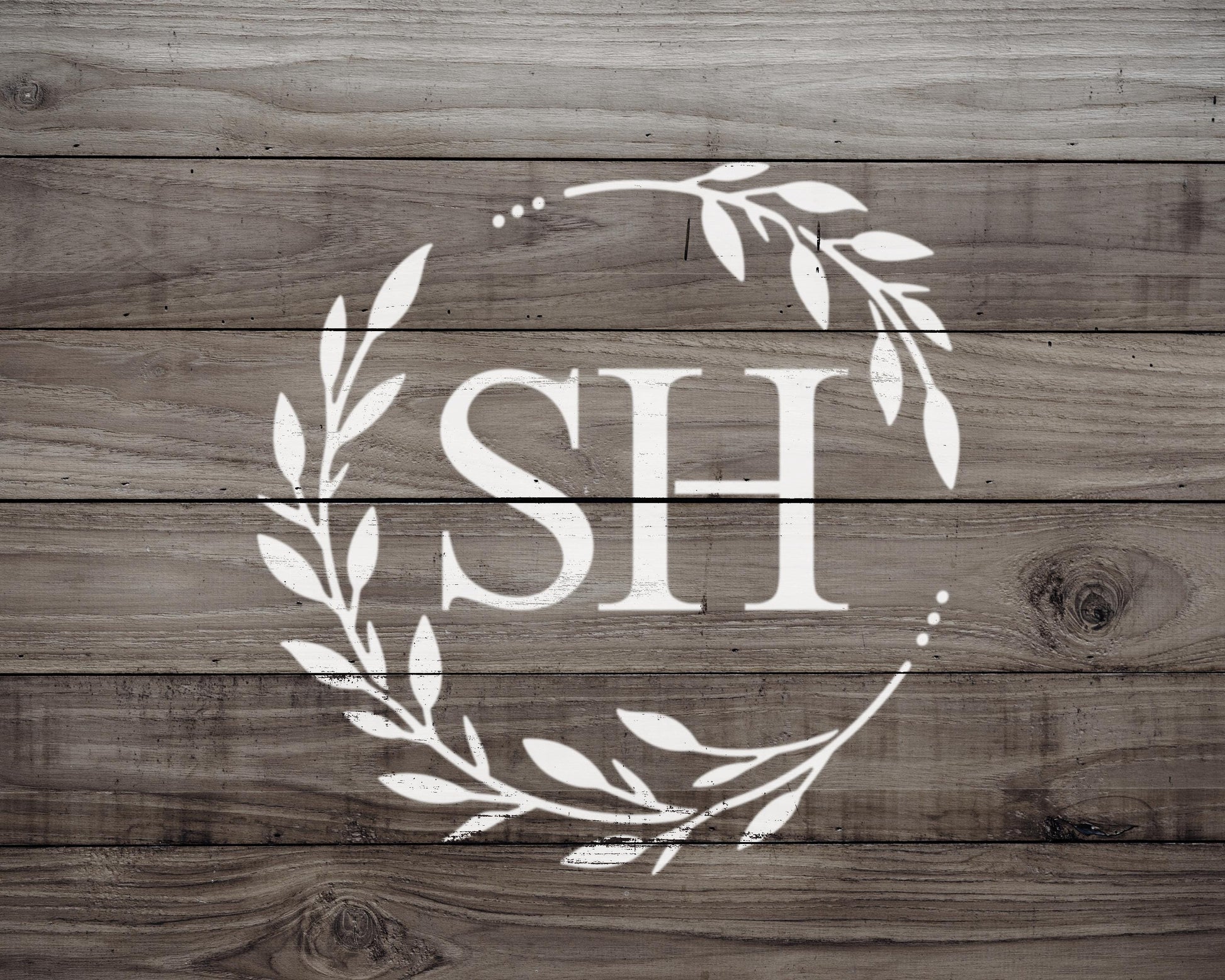 A monogrammed logo consisting of the letters "SH" surrounded by a wreath of leaves on a wooden background.