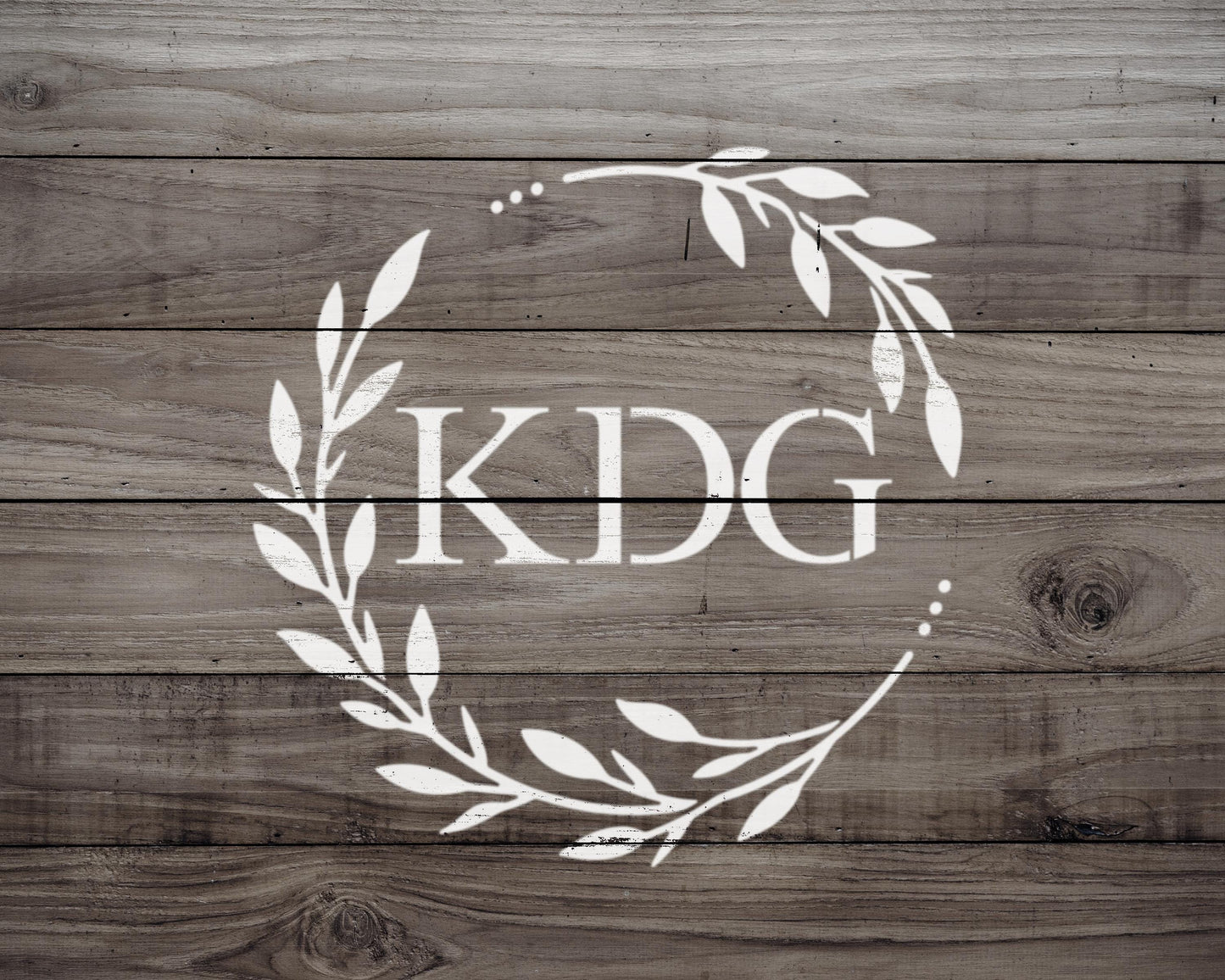 a logo with the letters "KDG" in a wreath design on a wooden background.