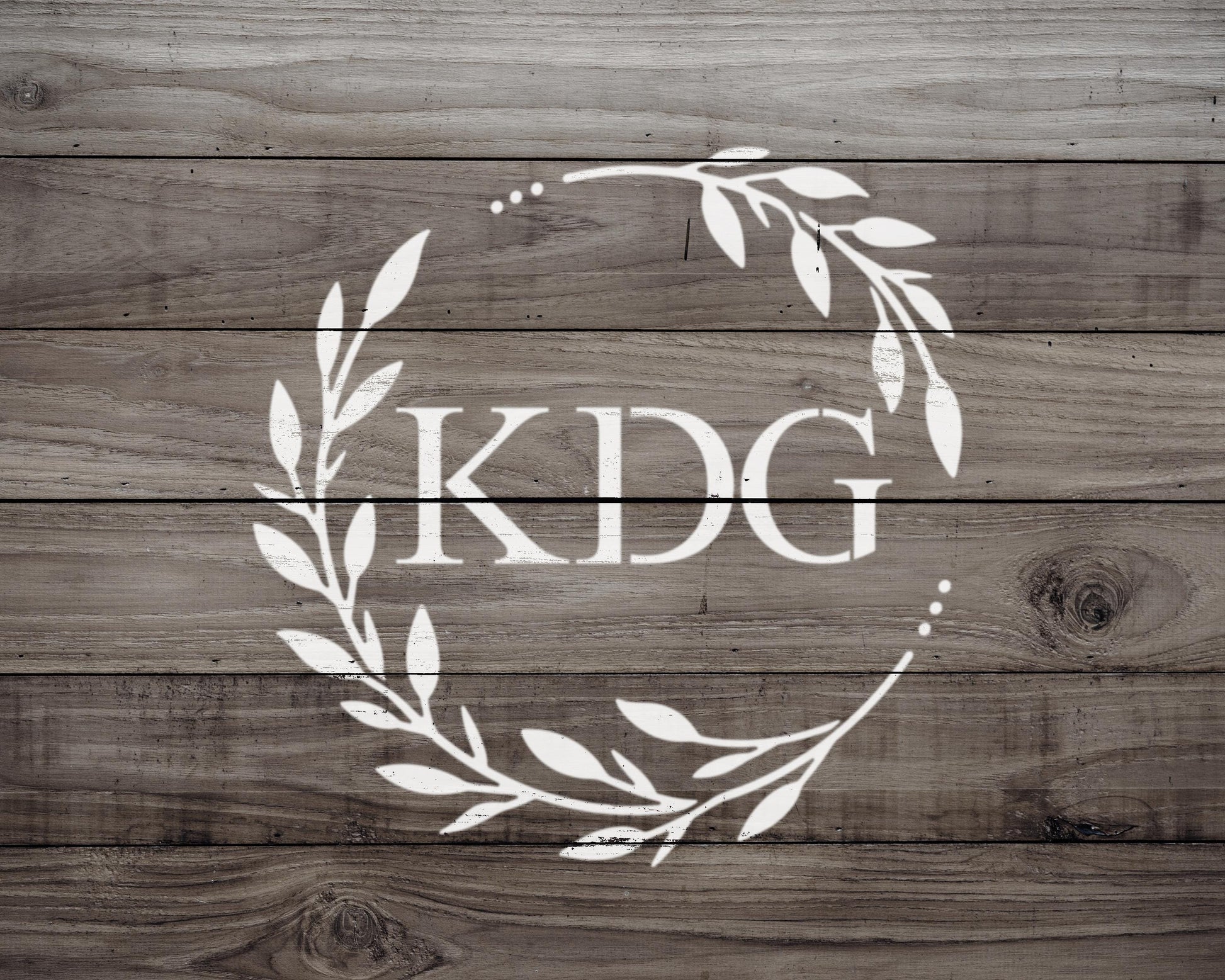 a logo with the letters "KDG" in a wreath design on a wooden background.