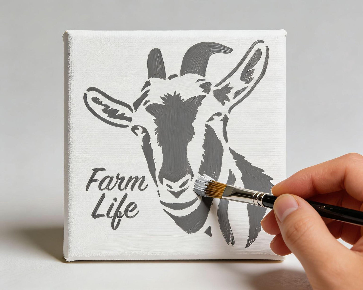 A hand is painting a canvas with a black and white illustration of a goat's head, which is labeled "Farm Life".