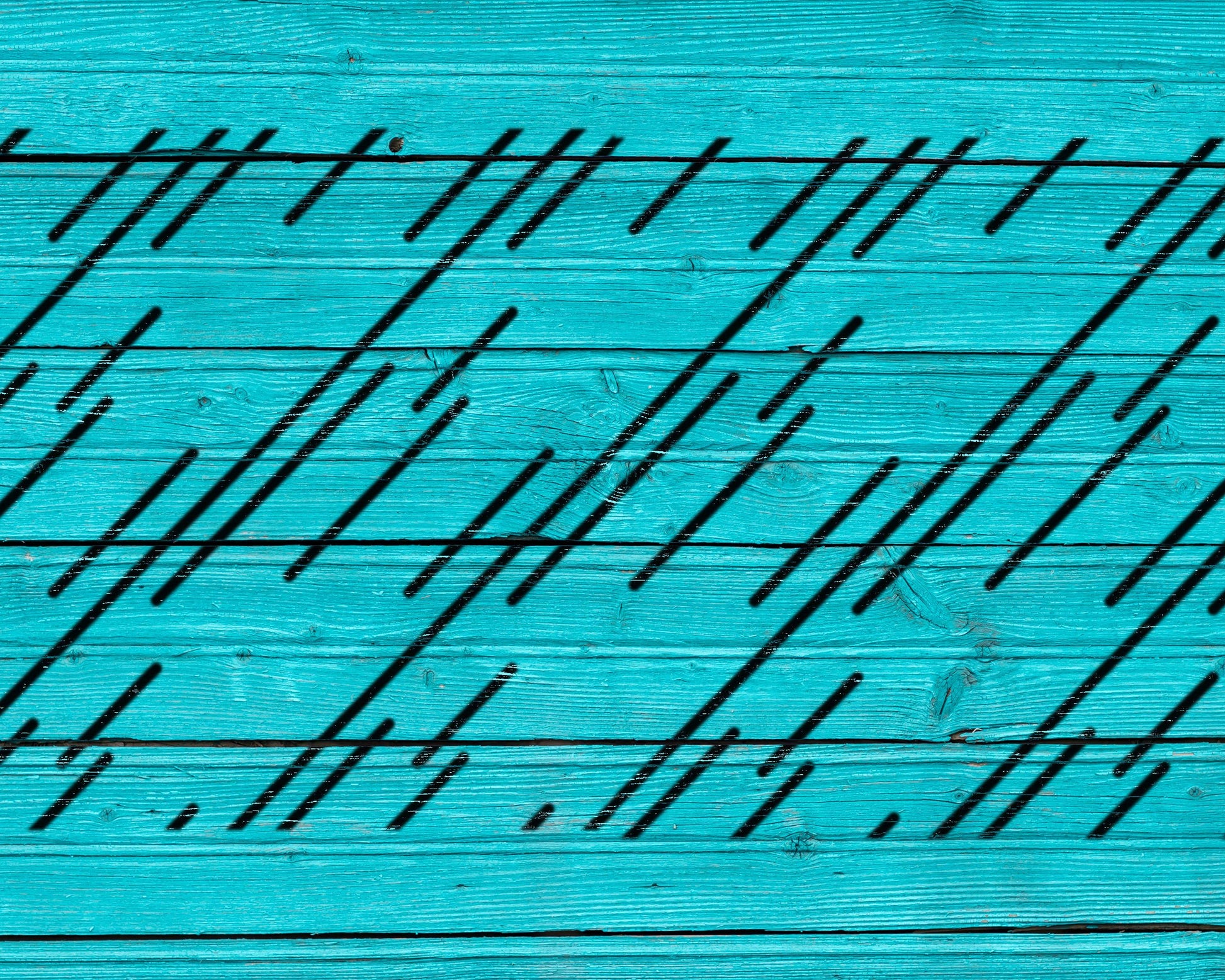 a close-up view of a turquoise wooden surface with diagonal black lines intersecting the surface.
