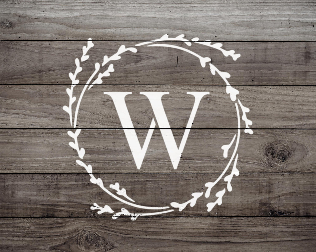 A monogrammed white letter "W" is displayed on a wooden background.