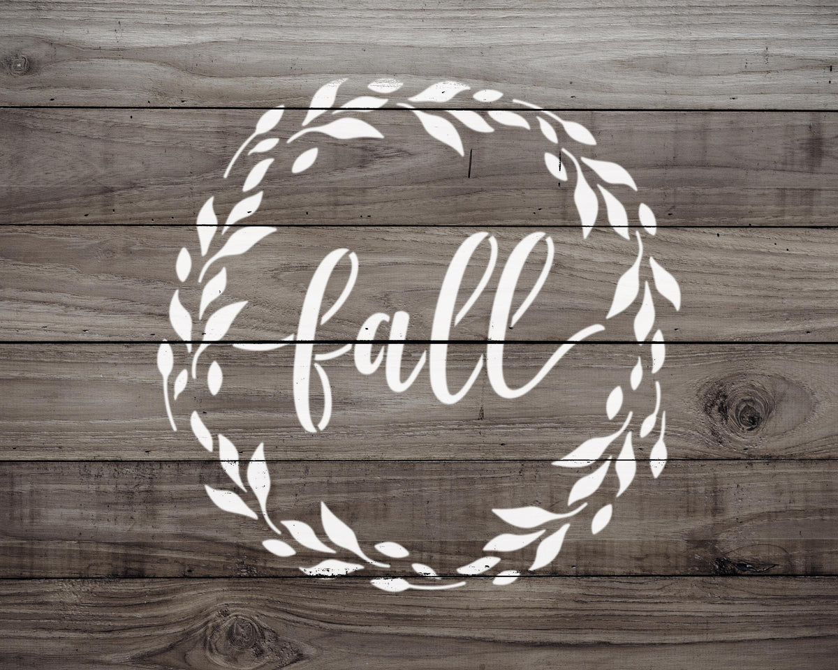 a wreath with the word "fall" written inside it, set against a wooden background.