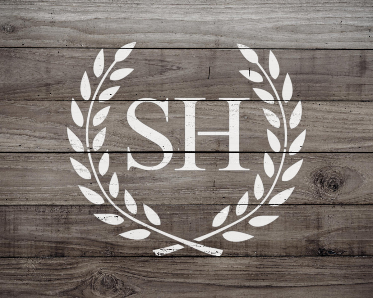 a monogrammed logo consisting of the letters "SH" within a laurel wreath design on a wooden background.
