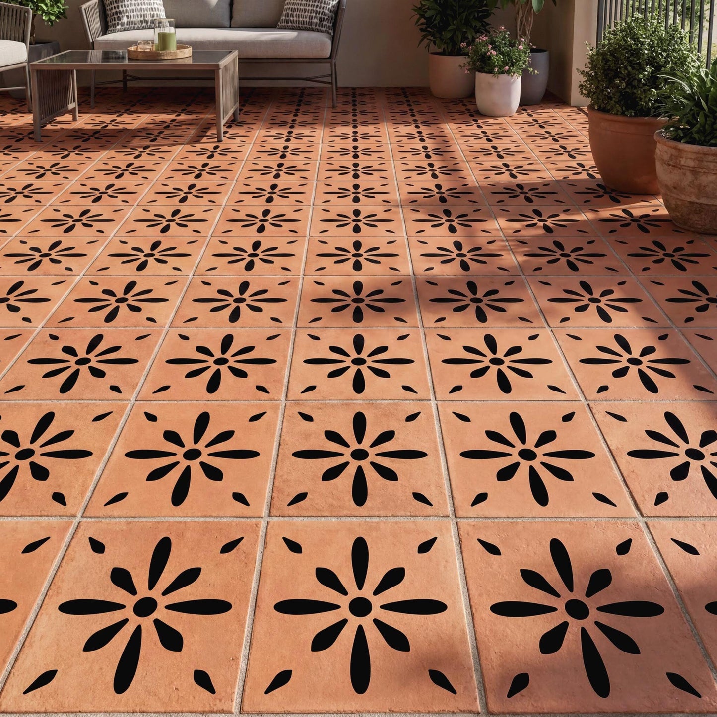a tiled floor with a repeating pattern of black and orange flowers. The floor is made of small square tiles arranged in a grid-like pattern. There are also potted plants placed around the room, adding a touch of greenery to the space.