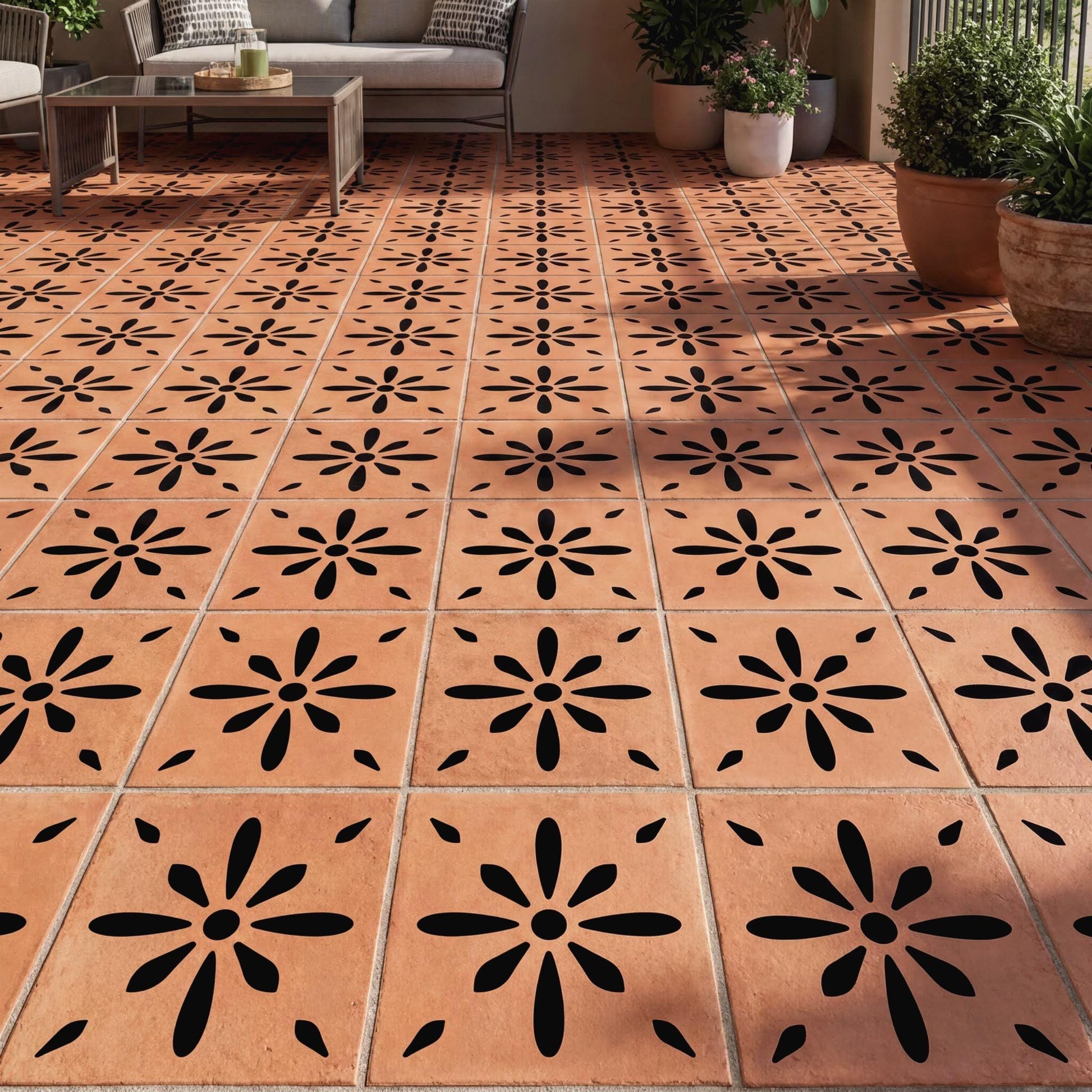 a tiled floor with a repeating pattern of black and orange flowers. The floor is made of small square tiles arranged in a grid-like pattern. There are also potted plants placed around the room, adding a touch of greenery to the space.