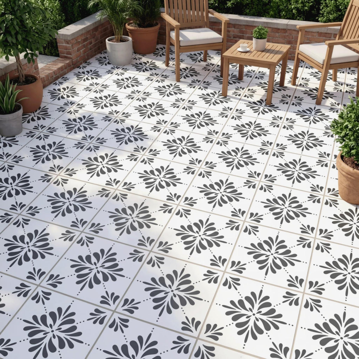a patio area with a black and white tile floor, each tile adorned with a stylized floral pattern. The patio is furnished with two wooden chairs and a small wooden table, creating a cozy outdoor seating area. The patio is surrounded by potted plants, adding a touch of greenery to the space.