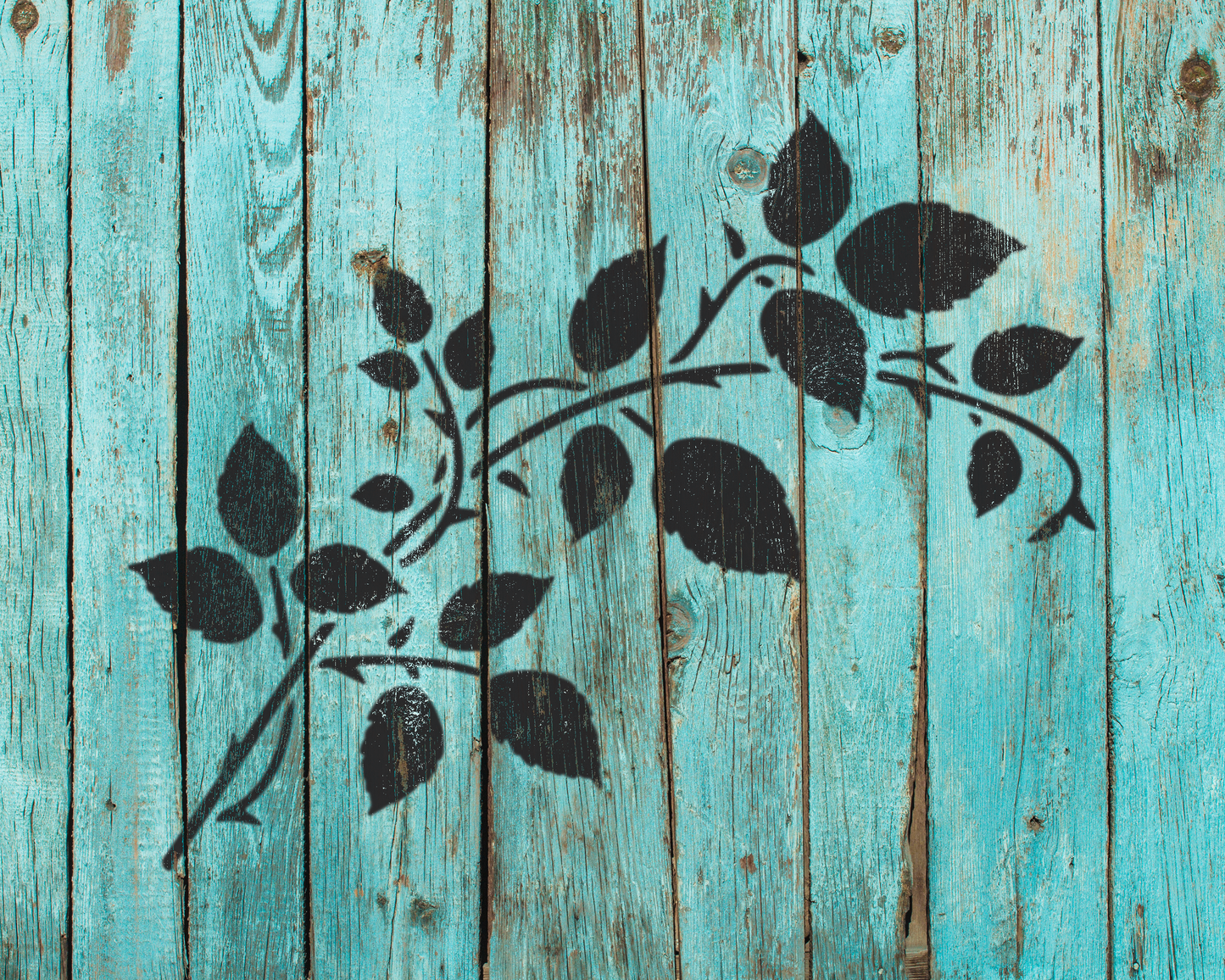 a close-up view of a weathered wooden surface with a black leaf stencil design.