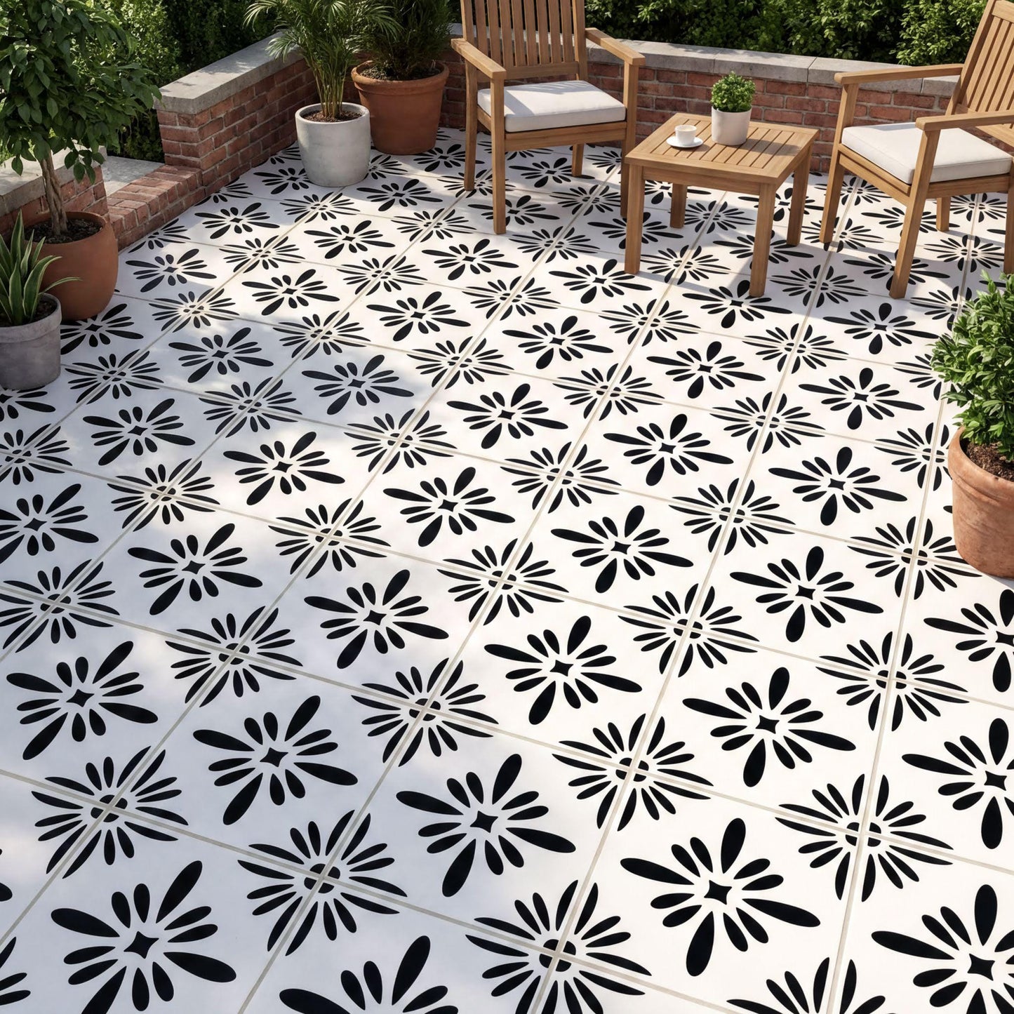 a patio area with a black and white tile floor, each tile adorned with a black flower design. The patio is furnished with two wooden chairs and a small wooden table, creating a cozy outdoor seating area. The patio is surrounded by potted plants, adding a touch of greenery to the space.