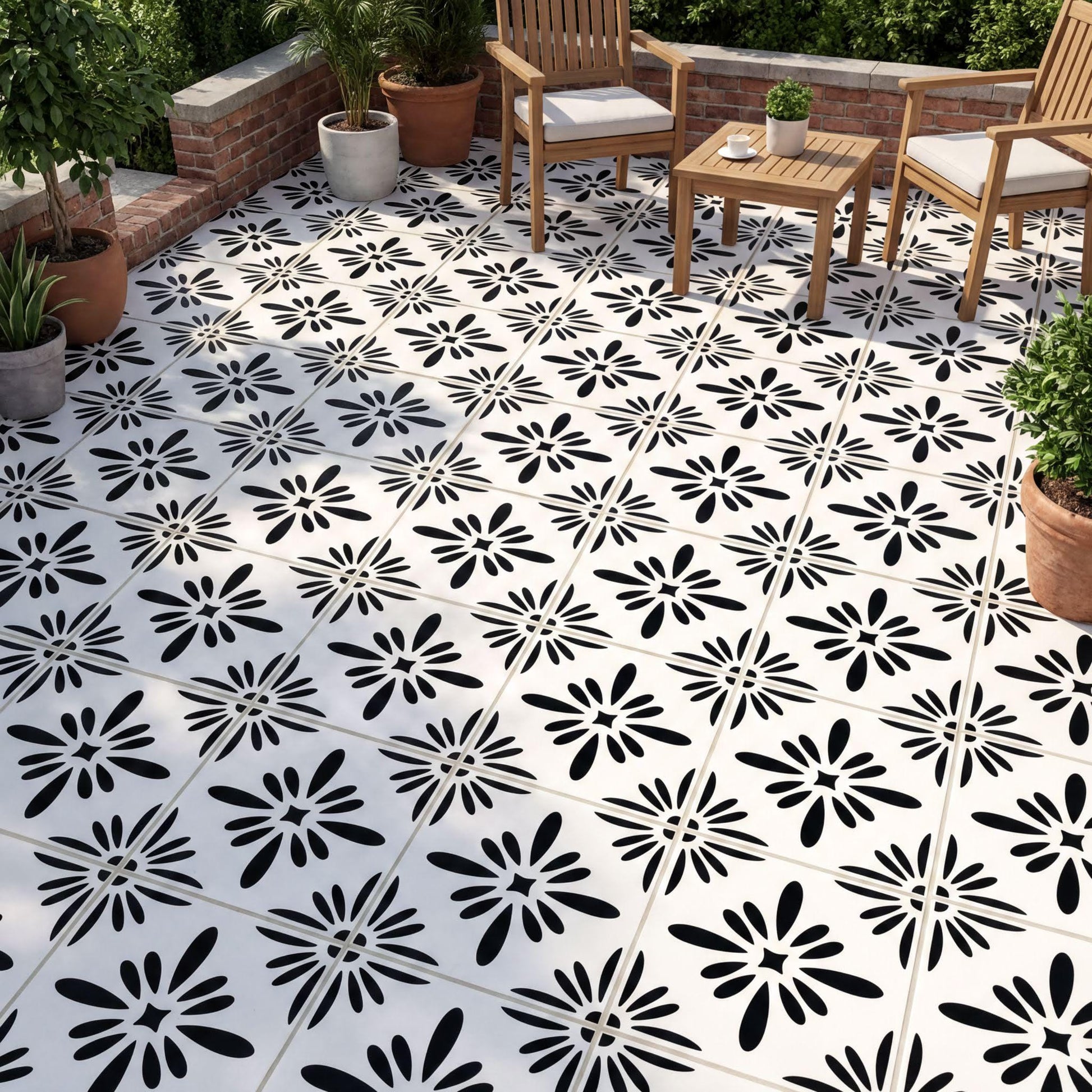 a patio area with a black and white tile floor, each tile adorned with a black flower design. The patio is furnished with two wooden chairs and a small wooden table, creating a cozy outdoor seating area. The patio is surrounded by potted plants, adding a touch of greenery to the space.