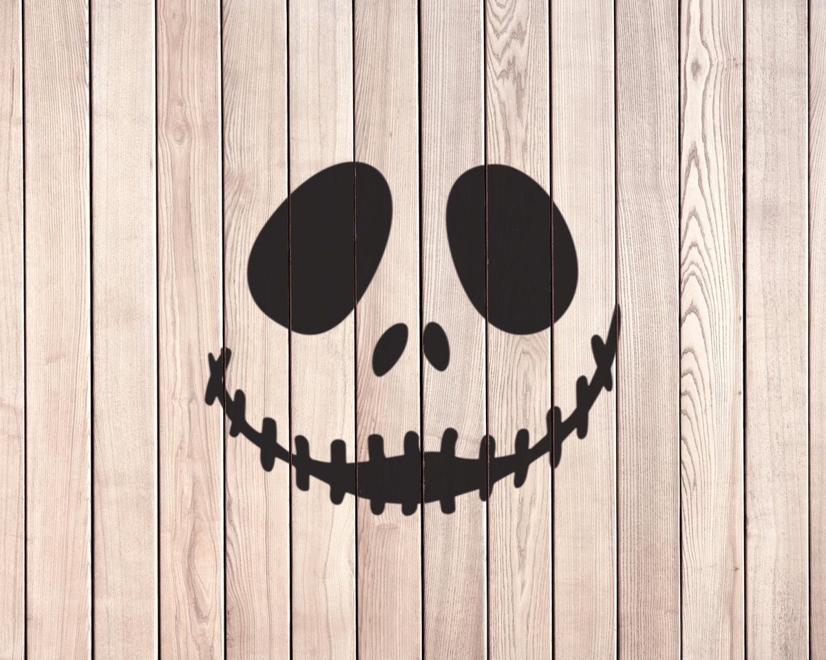 A silhouette of a skeleton head with a smiley face drawn on a wooden background.