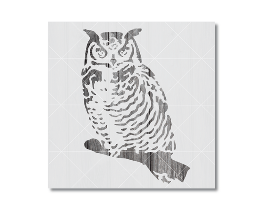 A silhouette of an owl sitting on a branch.