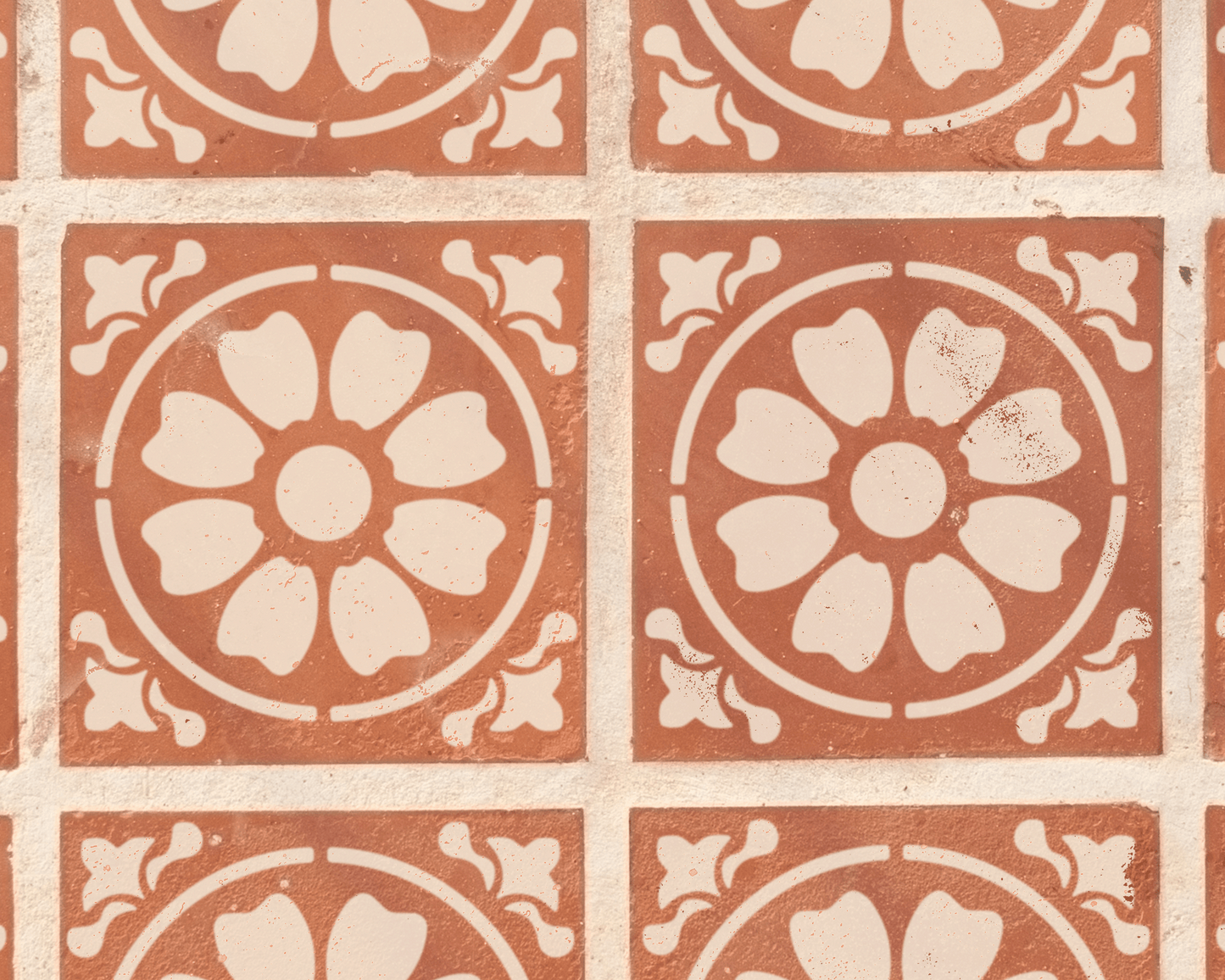 a repeating pattern of circular floral designs on a brick wall.