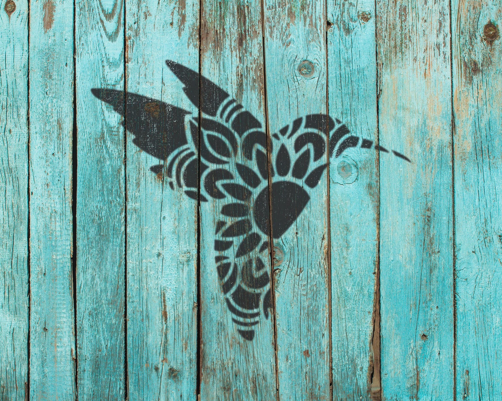 a black silhouette of a bird, possibly a hummingbird, against a blue wooden background.